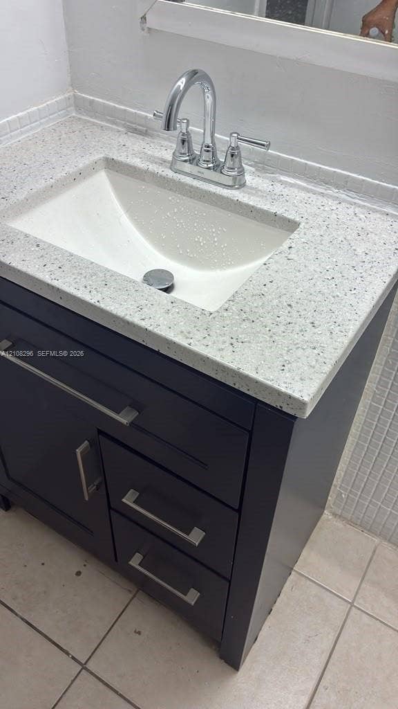 1800 Sans Souci Boulevard, #340, North Miami, North Miami, FL 33181 Bathroom vanity featuring a dark-finish cabinet with satin nickel hardware, a speckled composite countertop, an integrated rectangular sink, and a high-arc chrome faucet