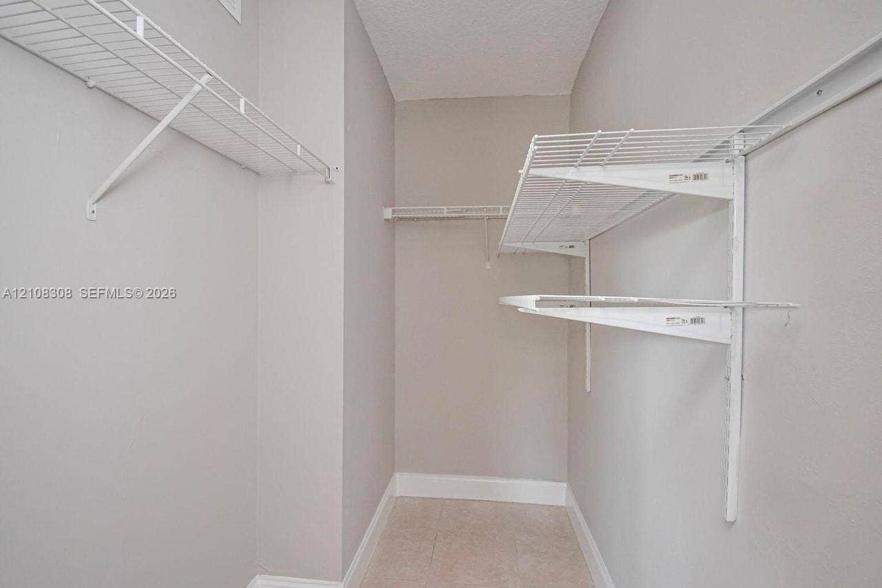 770 SE 2nd Avenue, #E201, Deerfield Beach, FL 33441 Walk-in storage space featuring neutral wall paint, tile flooring, and white wire shelving systems