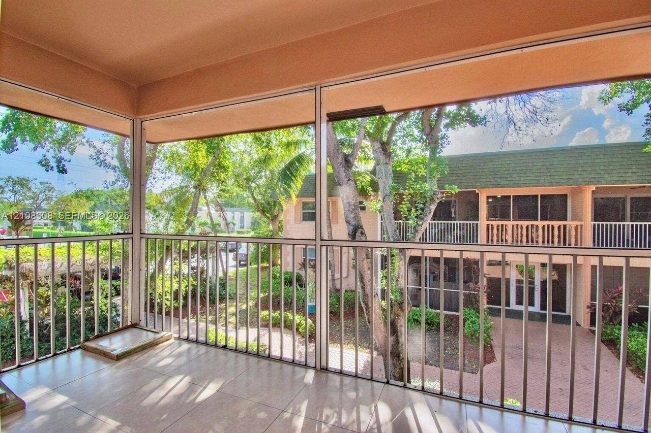 770 SE 2nd Avenue, #E201, Deerfield Beach, FL 33441 Screened balcony featuring light-toned tile flooring, metal frame enclosures, and vertical railings