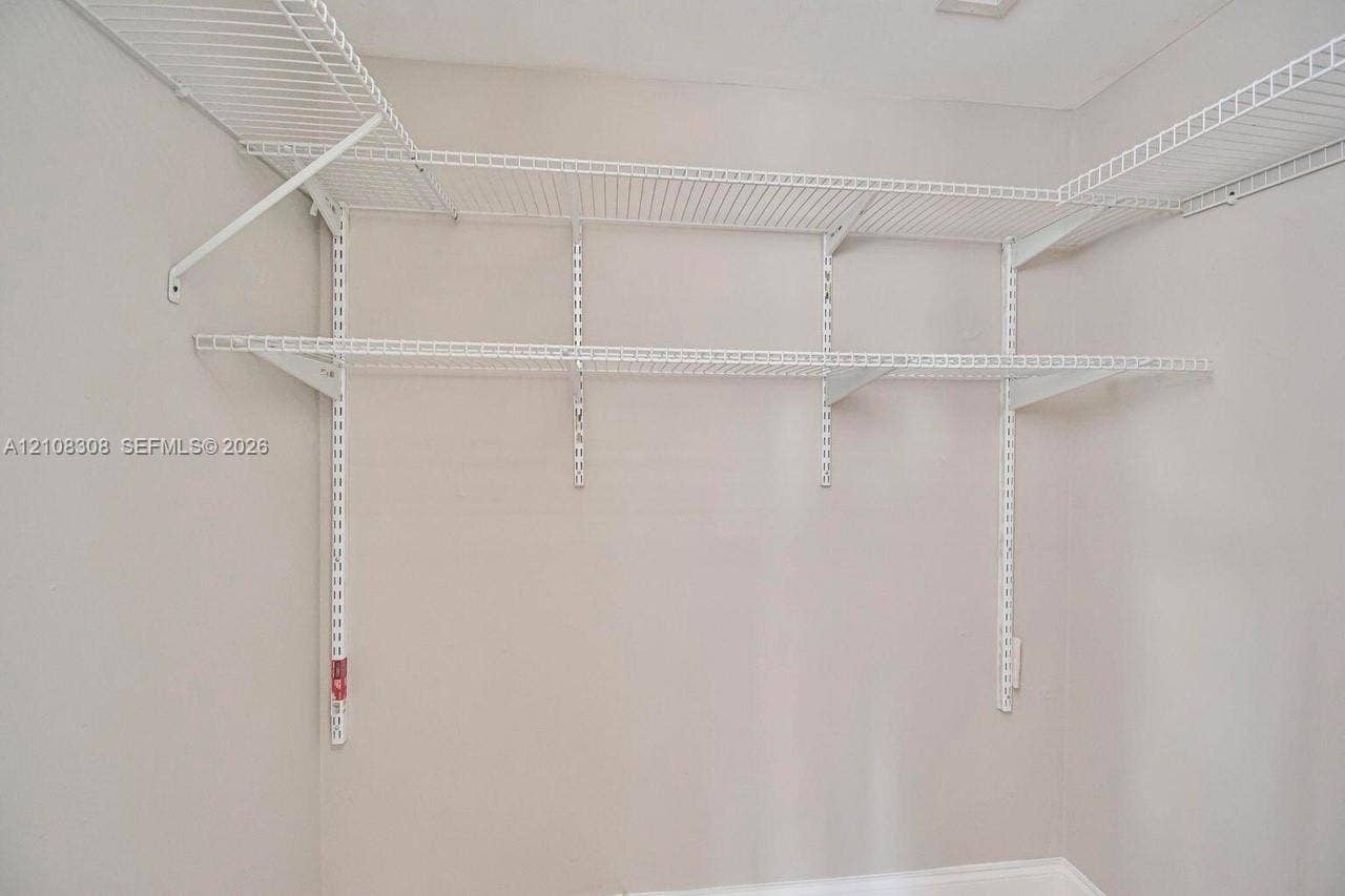 770 SE 2nd Avenue, #E201, Deerfield Beach, FL 33441 Wall-mounted white wire shelving system featuring tiered storage levels and adjustable support tracks