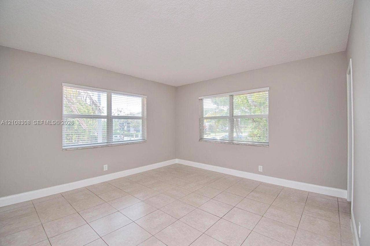 770 SE 2nd Avenue, #E201, Deerfield Beach, FL 33441 Neutral-toned interior featuring large windows, light-colored tile flooring, and a textured ceiling finish