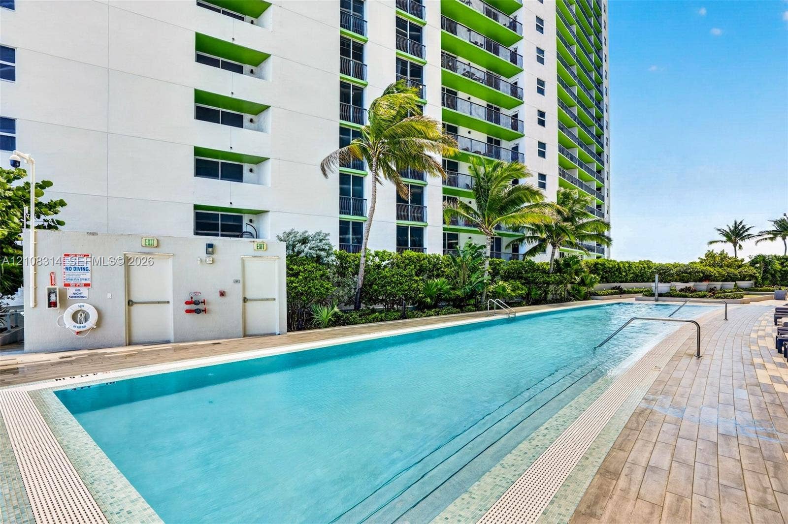 488 NE 18th Street, #4010, Miami, FL 33132 Linear lap pool featuring tile edging, stainless steel pool handrails, and wood-finish tiled decking