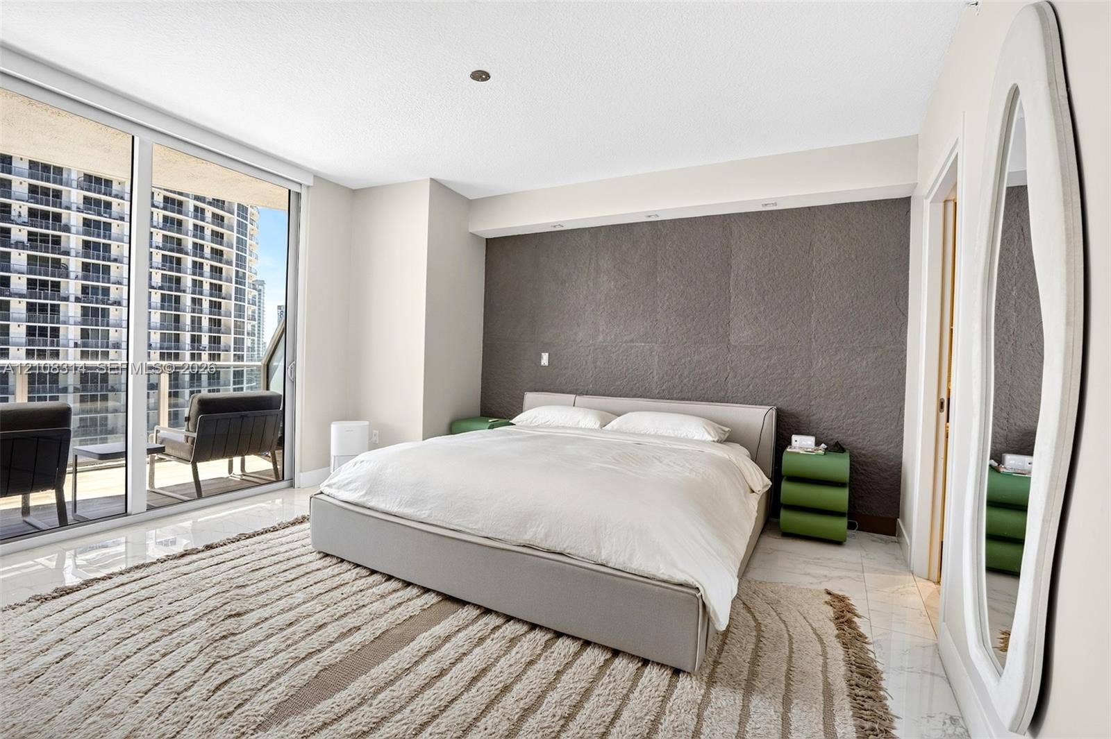 488 NE 18th Street, #4010, Miami, FL 33132 Floor-to-ceiling glass sliding doors, polished tile flooring, and a textured charcoal accent wall featuring recessed integrated lighting