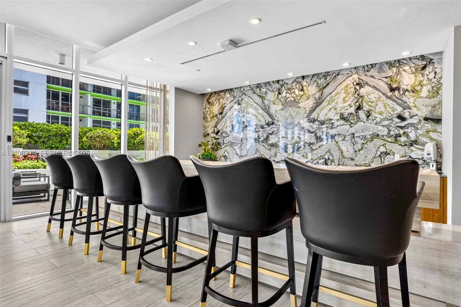 488 NE 18th Street, #4010, Miami, FL 33132 Stone accent wall with book-matched detailing, expansive floor-to-ceiling glass windows, recessed ceiling lighting, and neutral-toned tile flooring