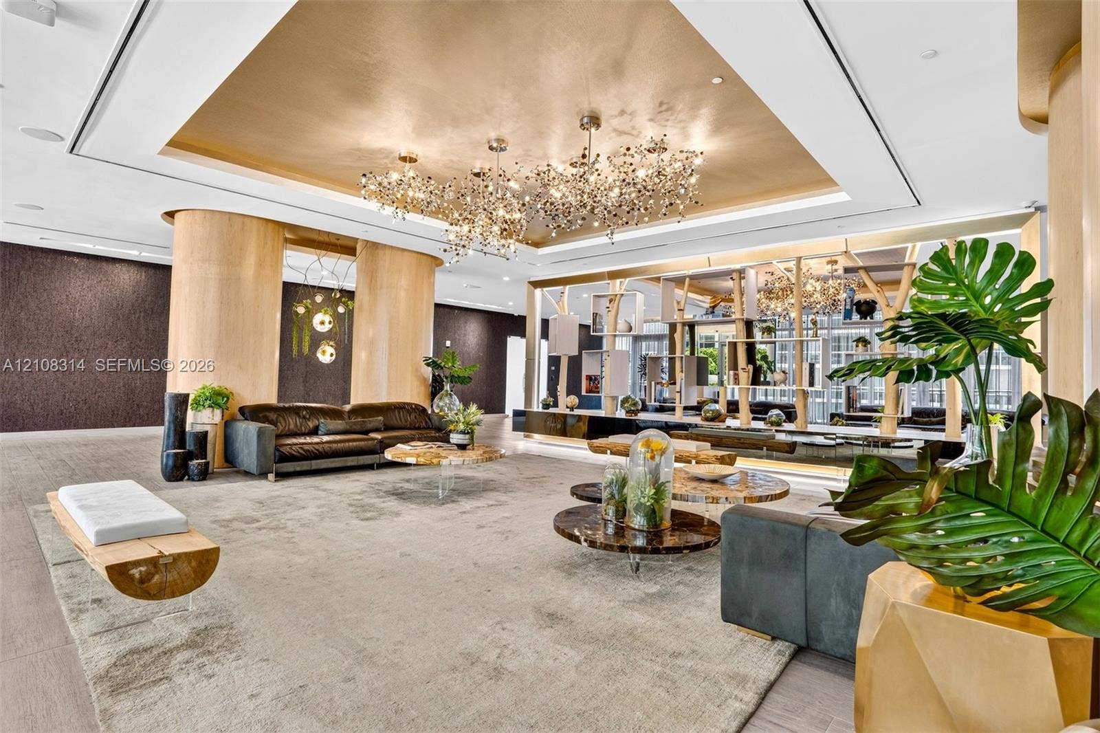 488 NE 18th Street, #4010, Miami, FL 33132 Metallic tray ceiling, large-scale multi-bulb crystal chandeliers, curved light-wood structural columns, integrated architectural shelving, and recessed lighting