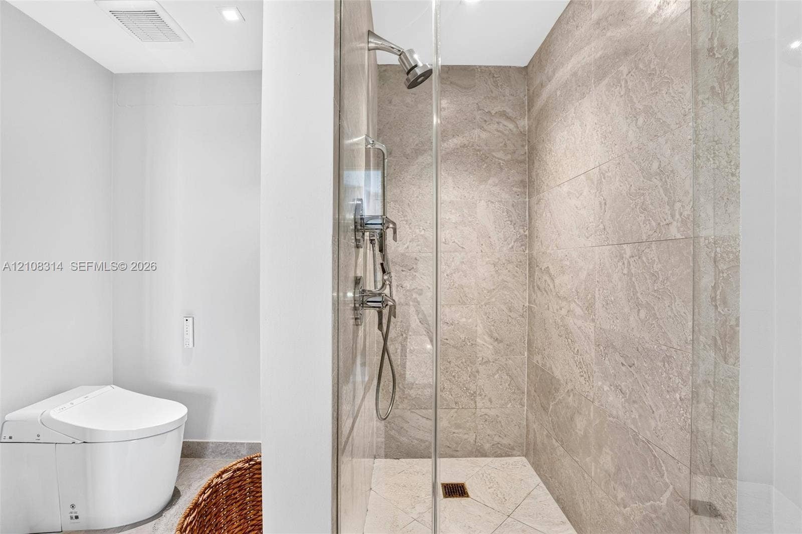 488 NE 18th Street, #4010, Miami, FL 33132 Walk-in shower with floor-to-ceiling stone-finish tile, glass enclosure, and wall-mounted shower system, paired with a one-piece low-profile toilet