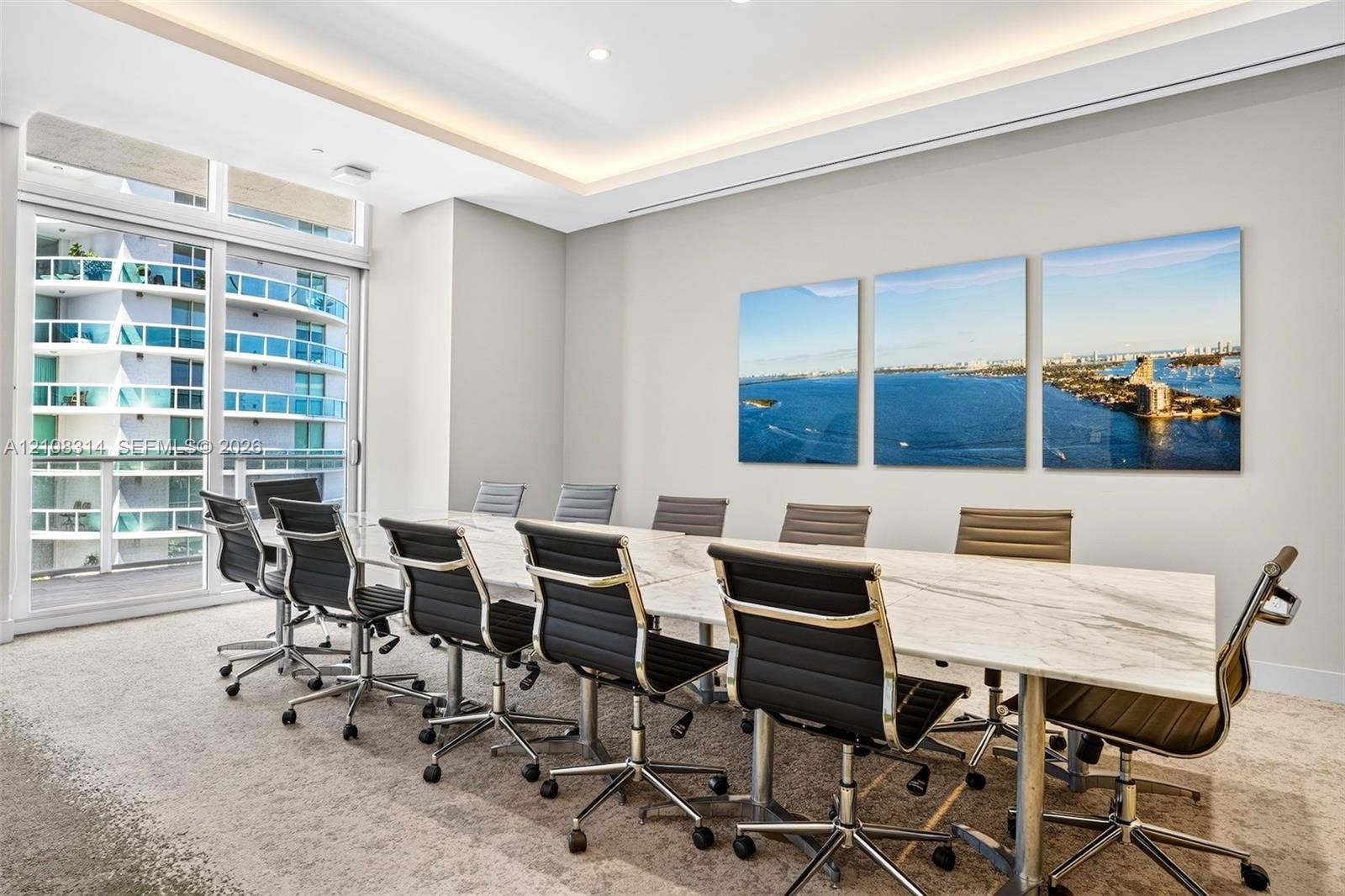 488 NE 18th Street, #4010, Miami, FL 33132 Conference room featuring tray ceiling with integrated perimeter lighting, floor-to-ceiling glass sliding door, and neutral carpeting