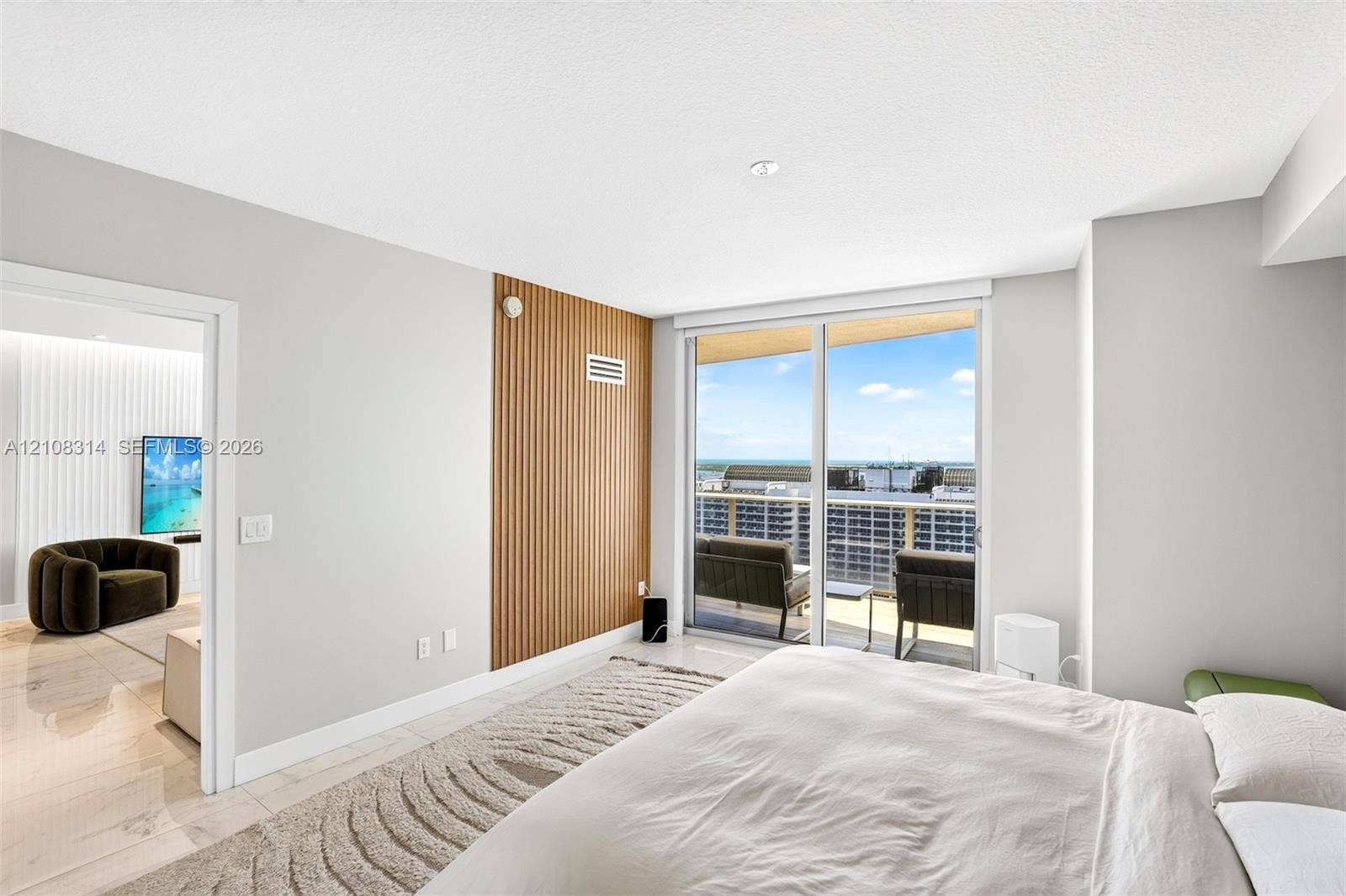 488 NE 18th Street, #4010, Miami, FL 33132 Room featuring floor-to-ceiling glass sliding doors, wood-slat accent wall, tile flooring, and integrated ceiling lighting