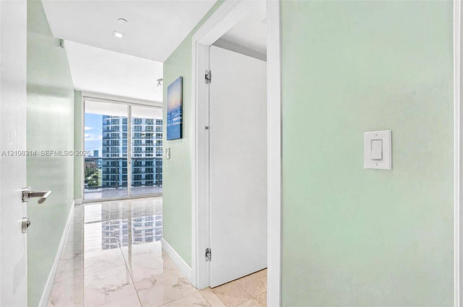 488 NE 18th Street, #4010, Miami, FL 33132 Hallway featuring large-format tile flooring, light-toned wall finishes, and floor-to-ceiling glass sliding doors