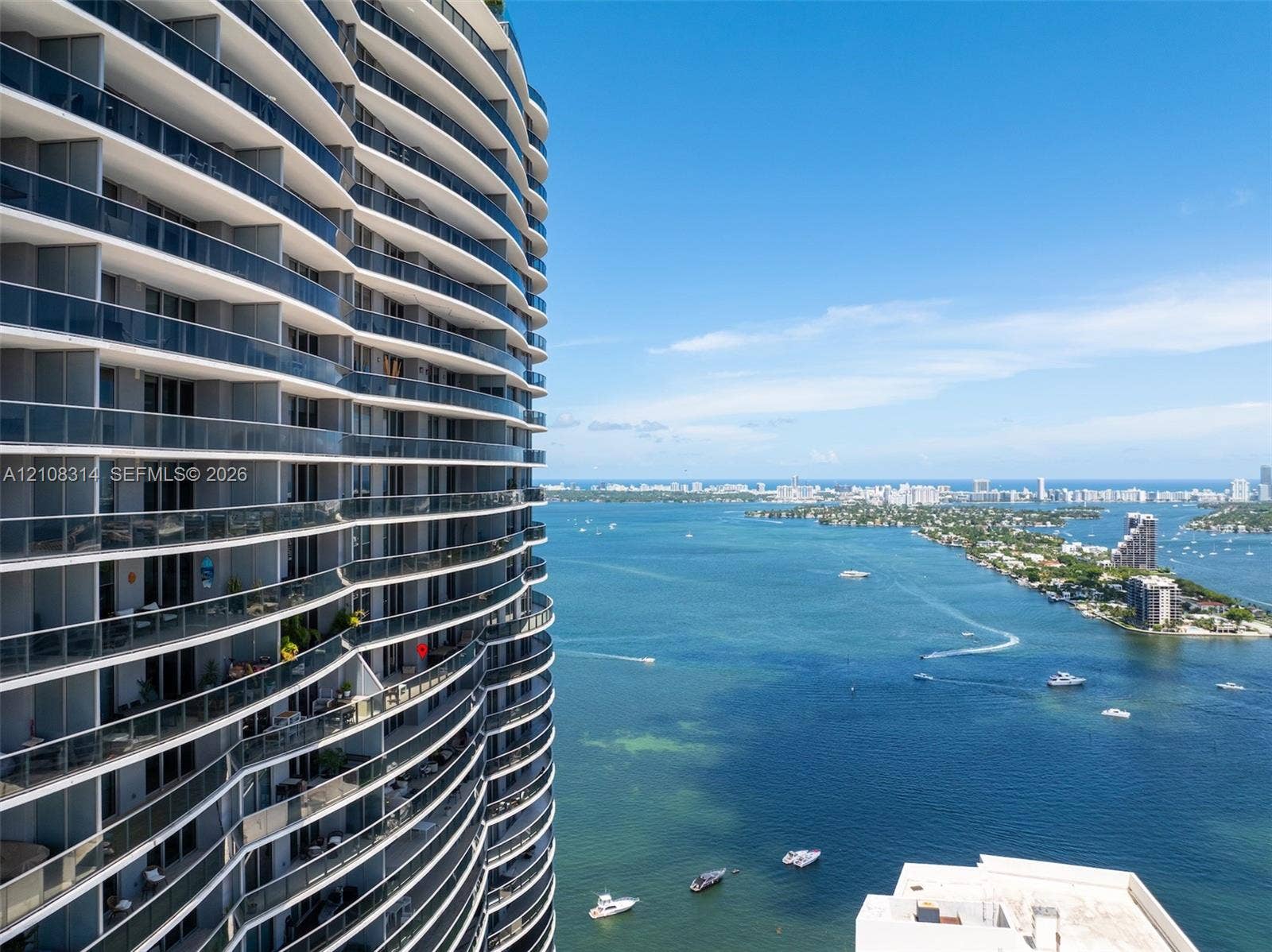 488 NE 18th Street, #4010, Miami, FL 33132 Curved high-rise exterior featuring floor-to-ceiling glass railings and tiered private balconies