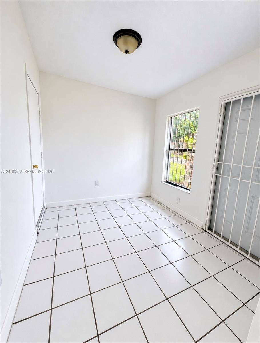 722 NW 7th Avenue, Homestead, FL 33030 Interior space featuring white tile flooring, flush-mount ceiling lighting, and a metal security door