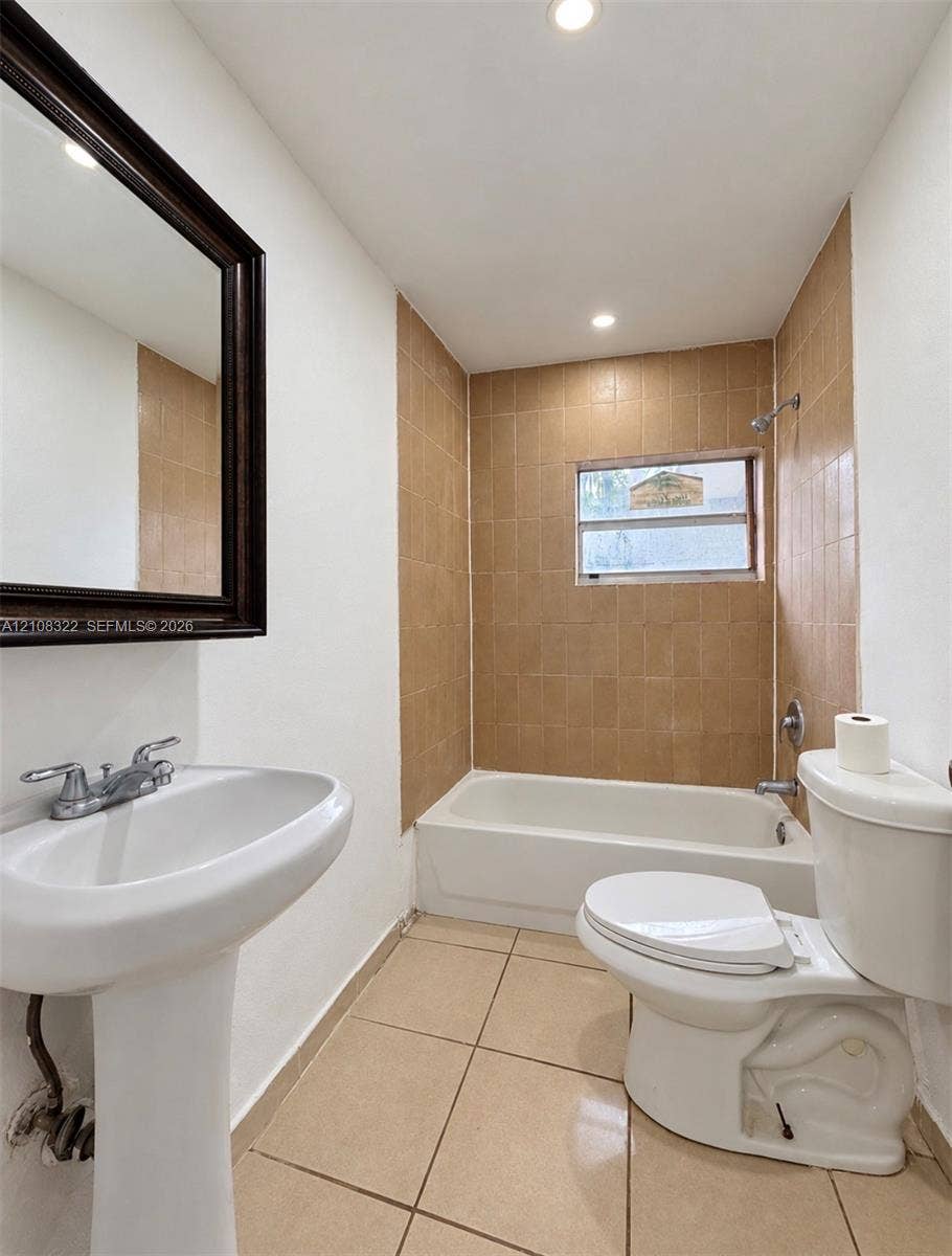 722 NW 7th Avenue, Homestead, FL 33030 Bathroom featuring a porcelain pedestal sink, ceramic tile flooring, a shower-tub combination with tiled surround, and a framed wall-mounted mirror