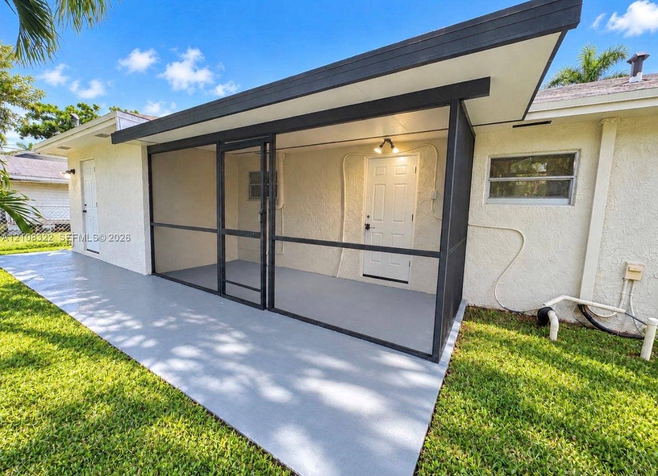 722 NW 7th Avenue, Homestead, FL 33030 Screened-in patio with a concrete floor, exterior lighting, and painted masonry siding