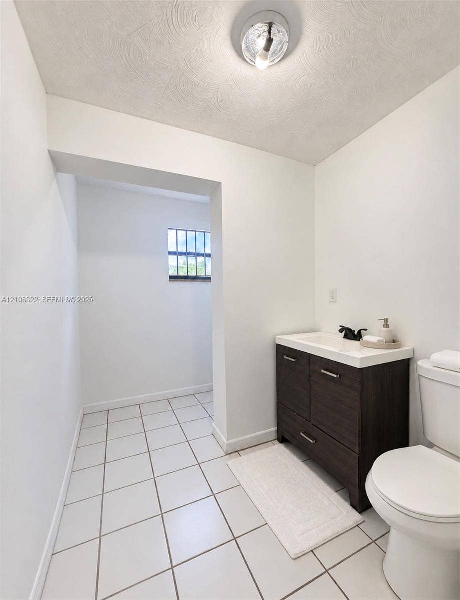 722 NW 7th Avenue, Homestead, FL 33030 Dark wood-finish vanity with a white countertop and matte black faucet, ceramic tile flooring, and flush-mount ceiling lighting