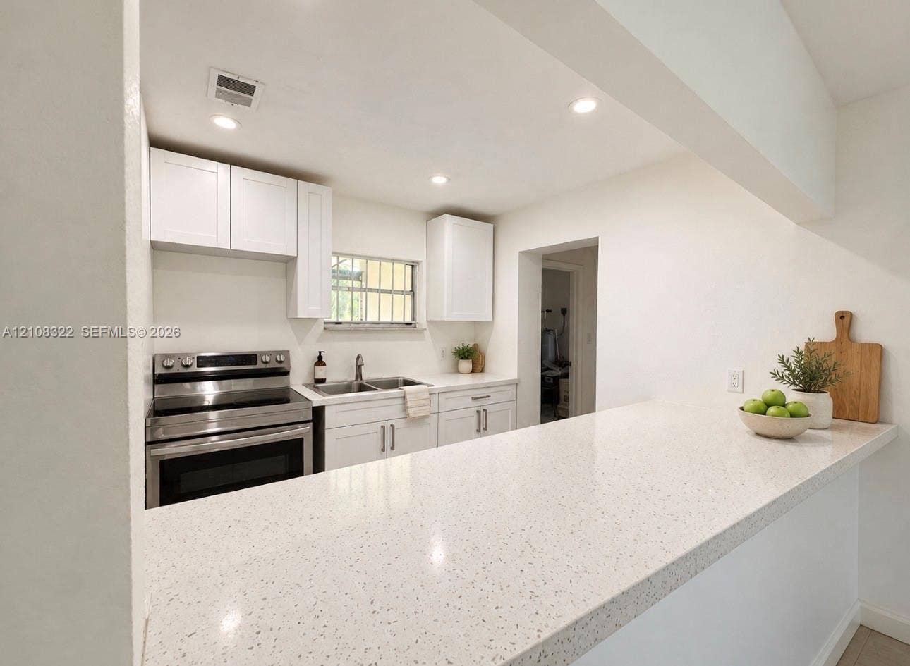 722 NW 7th Avenue, Homestead, FL 33030 Kitchen featuring white shaker-style cabinetry, a quartz countertop breakfast bar, recessed lighting, and stainless steel appliances