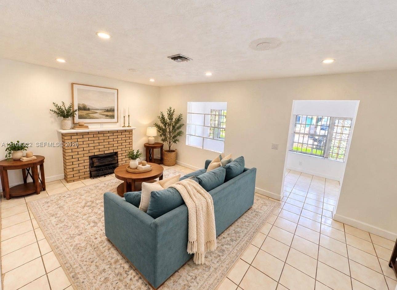 722 NW 7th Avenue, Homestead, FL 33030 Living area featuring light-toned tile flooring, a brick masonry fireplace with a mantel, recessed ceiling lighting, and windows with decorative geometric grilles