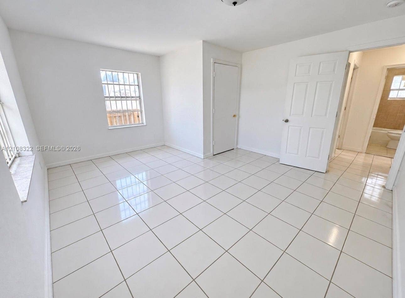 722 NW 7th Avenue, Homestead, FL 33030 Neutral-toned interior space featuring polished tile flooring, white-painted walls, and six-panel interior doors
