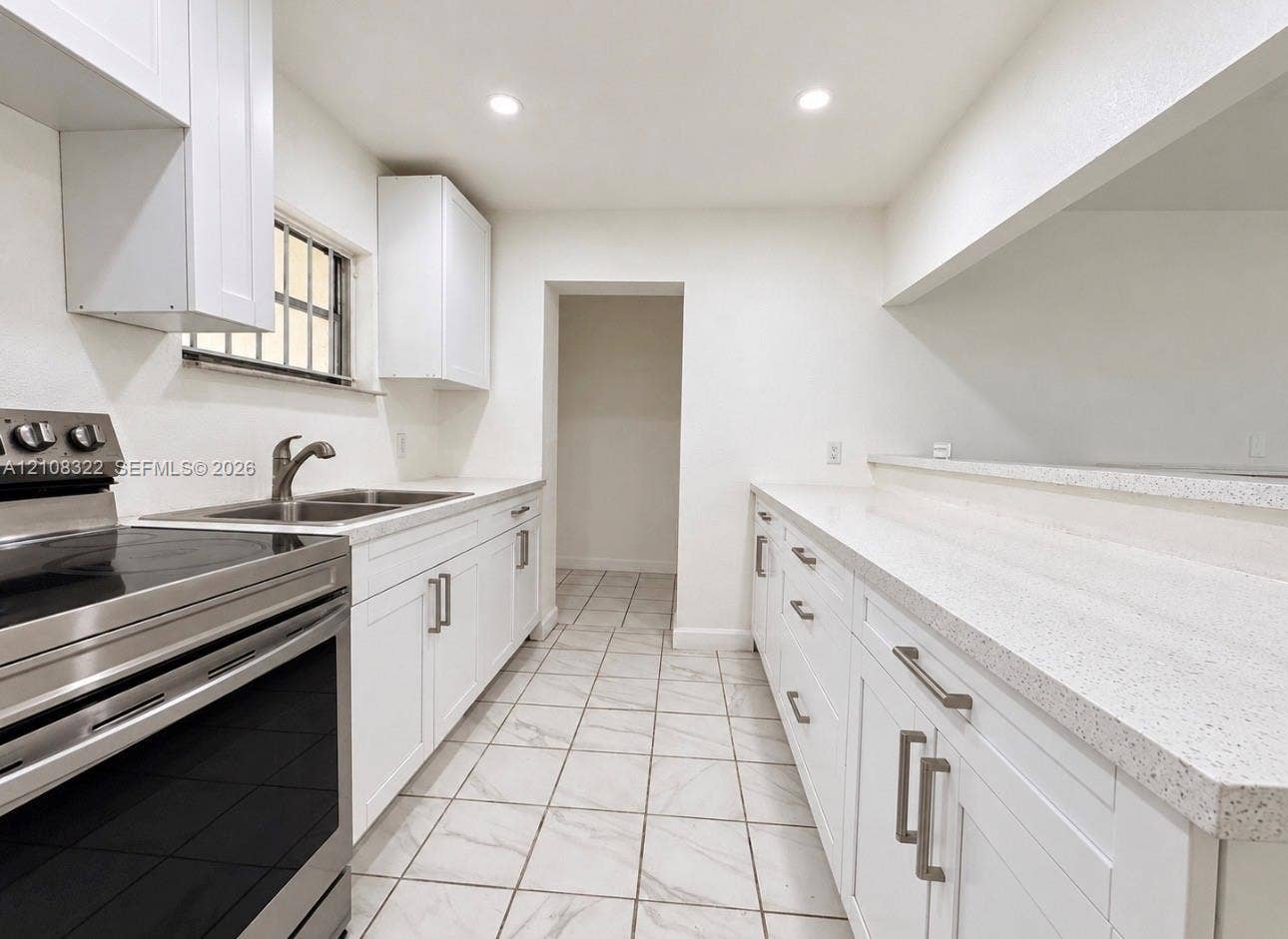 722 NW 7th Avenue, Homestead, FL 33030 Kitchen featuring white cabinetry with brushed metal hardware, solid-surface countertops, recessed lighting, and tile flooring