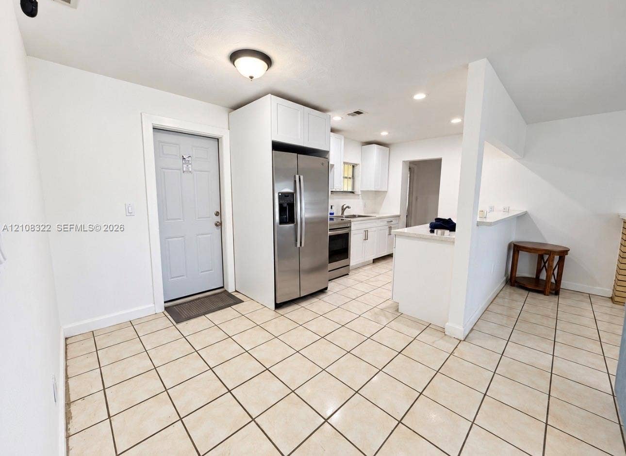 722 NW 7th Avenue, Homestead, FL 33030 Kitchen featuring white cabinetry, stainless steel appliances, ceramic tile flooring, and a breakfast bar