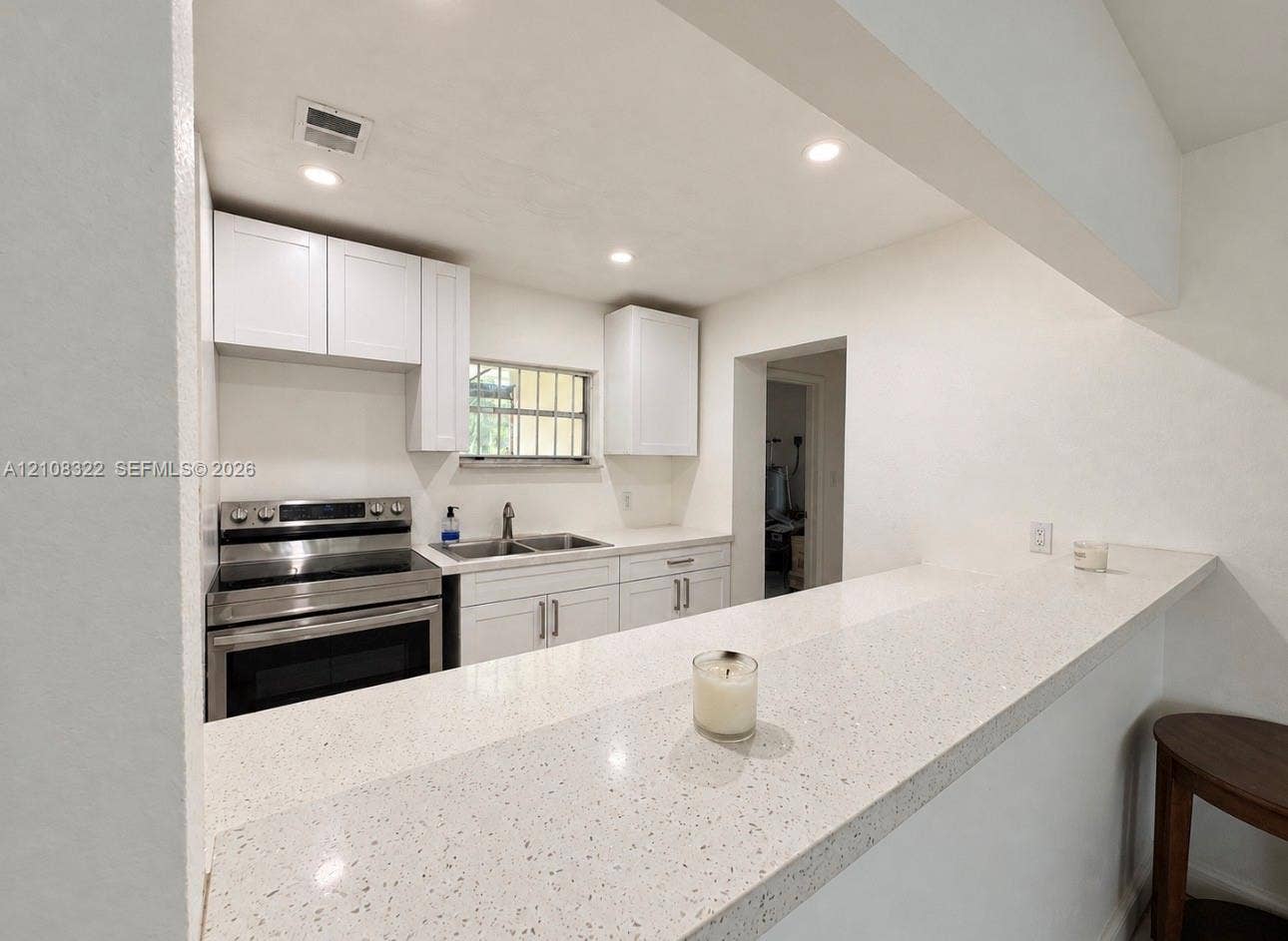 722 NW 7th Avenue, Homestead, FL 33030 Kitchen featuring white cabinetry, quartz countertops, a dual-basin stainless steel sink, and stainless steel range