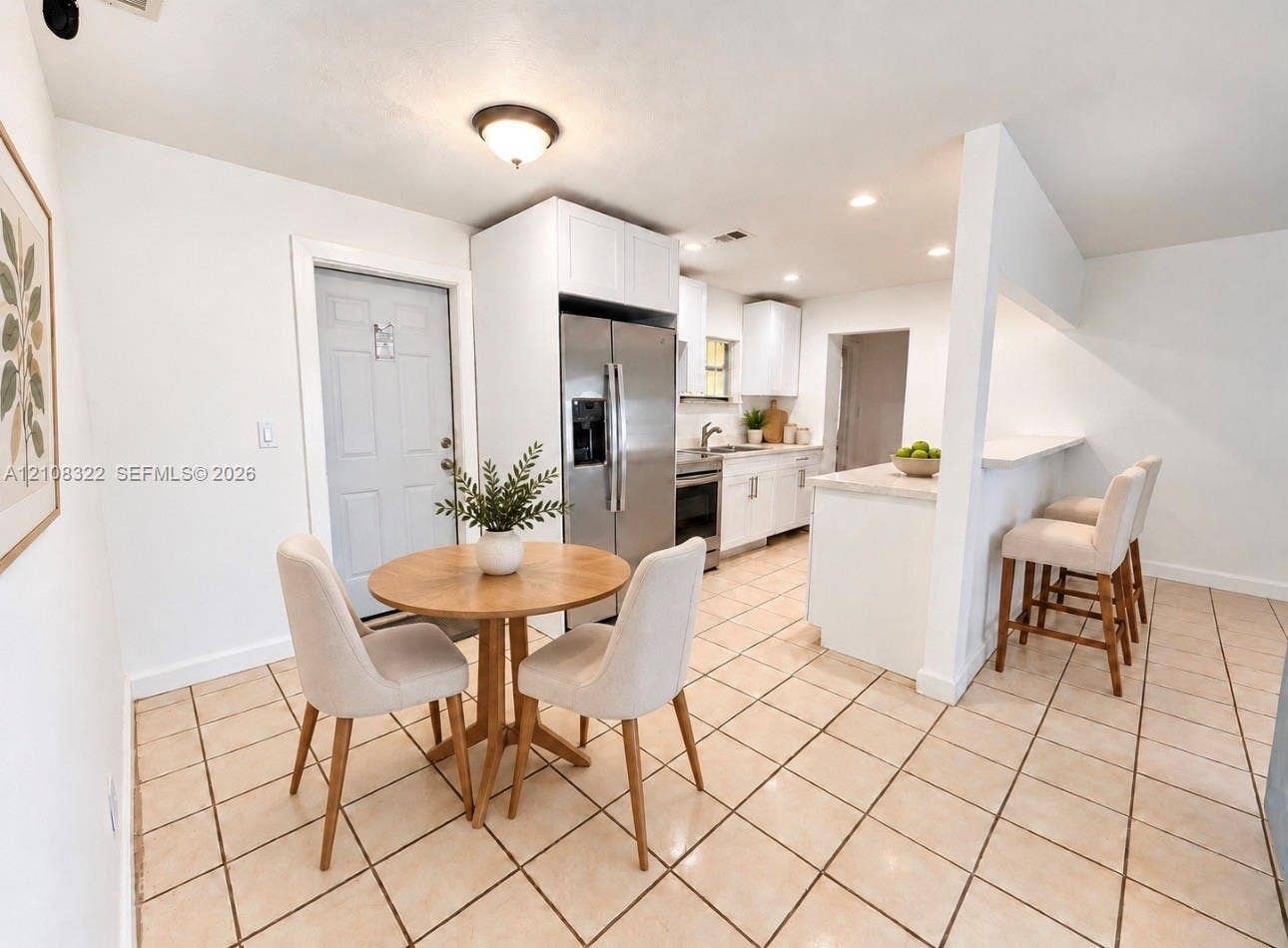 722 NW 7th Avenue, Homestead, FL 33030 Kitchen featuring white shaker-style cabinetry, stainless steel refrigerator, stone-surfaced breakfast bar, and light-toned floor tiling