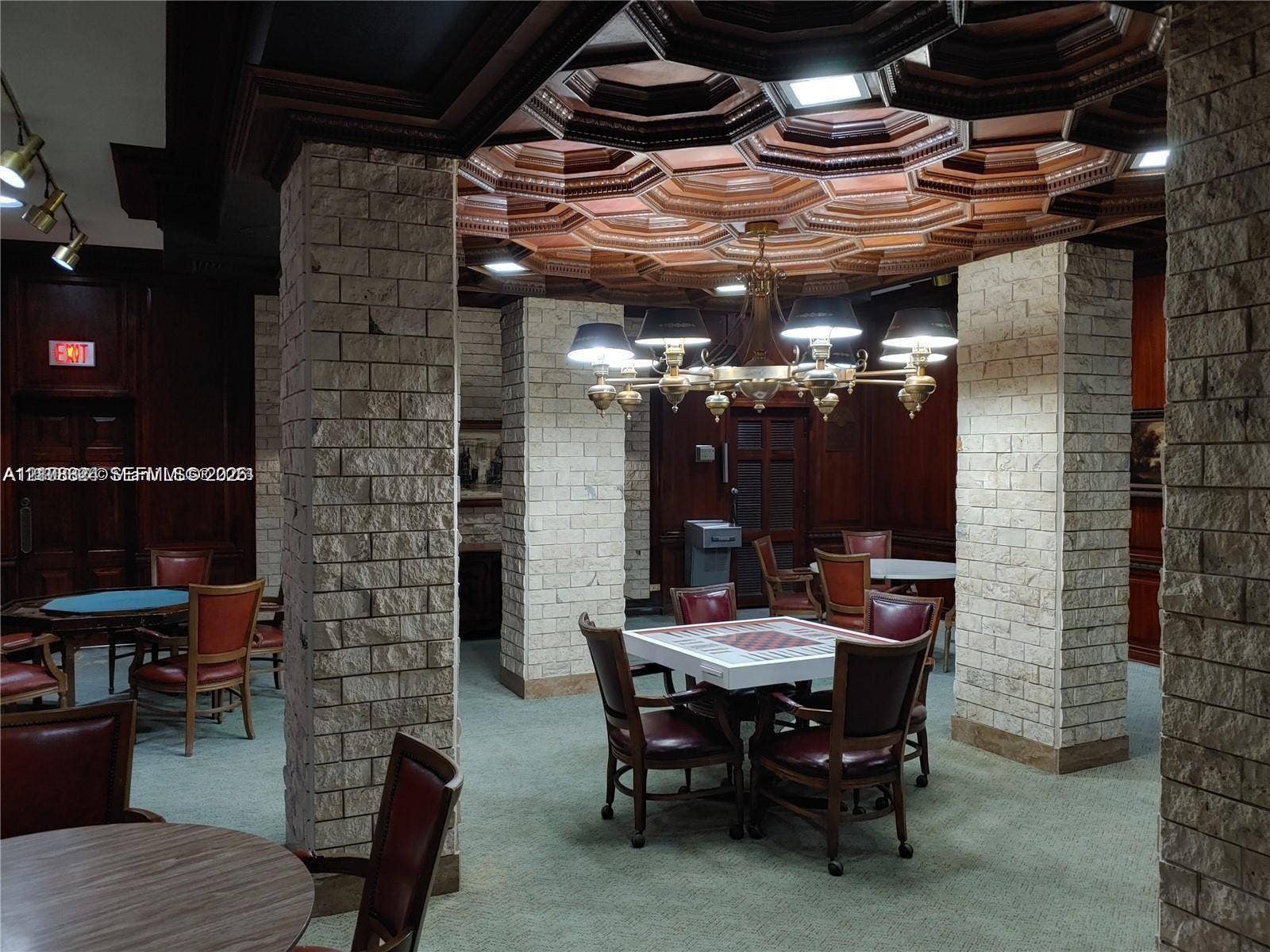 6039 Collins Avenue, #1208, Miami Beach, FL 33140 Custom coffered wood ceiling, stone-clad structural pillars, and dark wood-paneled walls