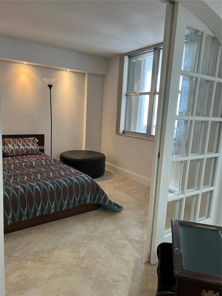 6039 Collins Avenue, #1208, Miami Beach, FL 33140 Neutral-toned stone flooring, recessed ceiling lighting, and white multi-pane French doors