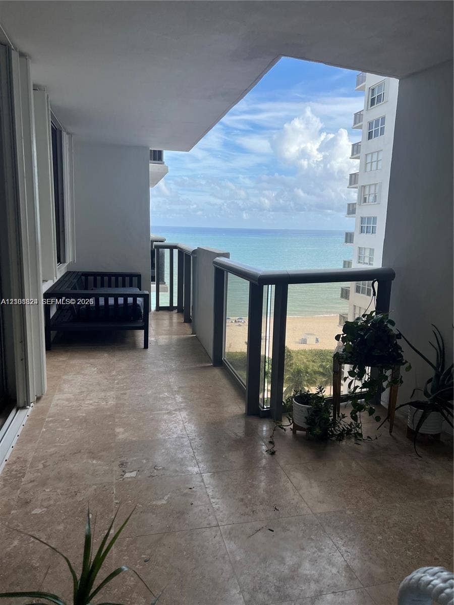 6039 Collins Avenue, #1208, Miami Beach, FL 33140 Covered balcony featuring stone flooring and a glass-paneled railing