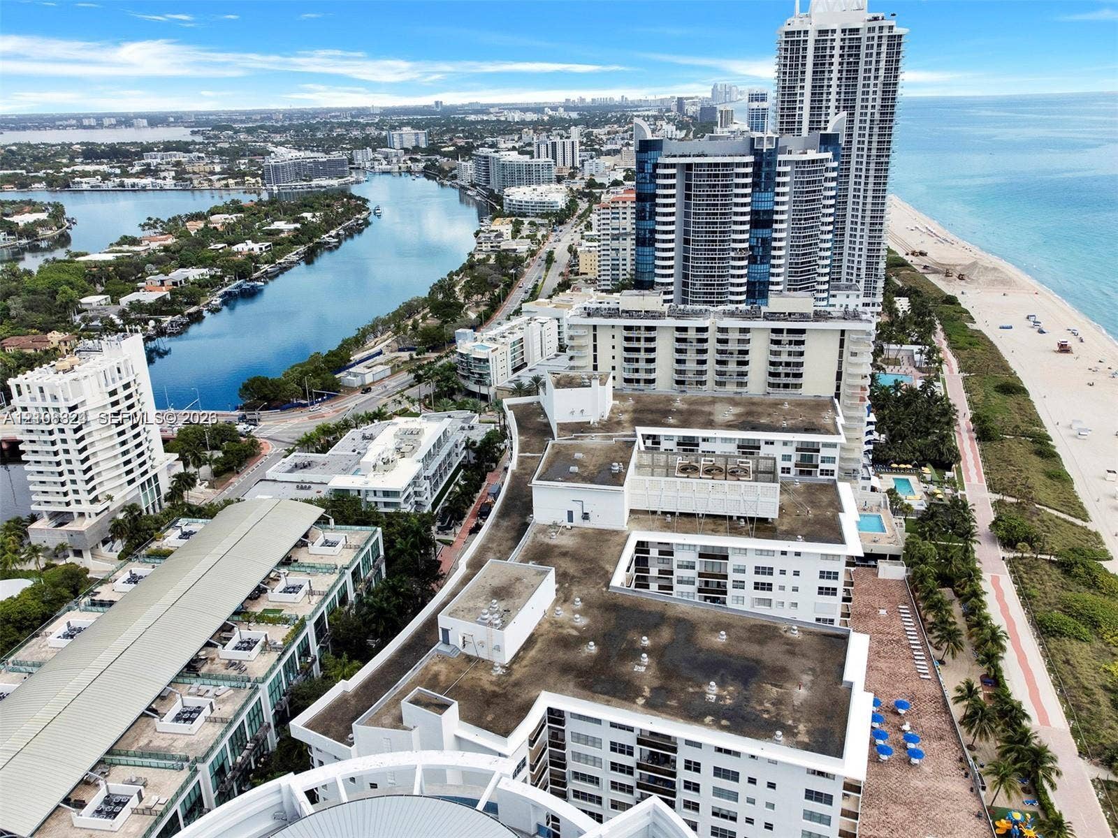 6039 Collins Avenue, #1208, Miami Beach, FL 33140 Aerial perspective of a multi-story coastal residential complex situated between the Atlantic Ocean and the Intracoastal Waterway, featuring expansive shoreline access, paved pedestrian paths, and proximity to regional maritime landmarks