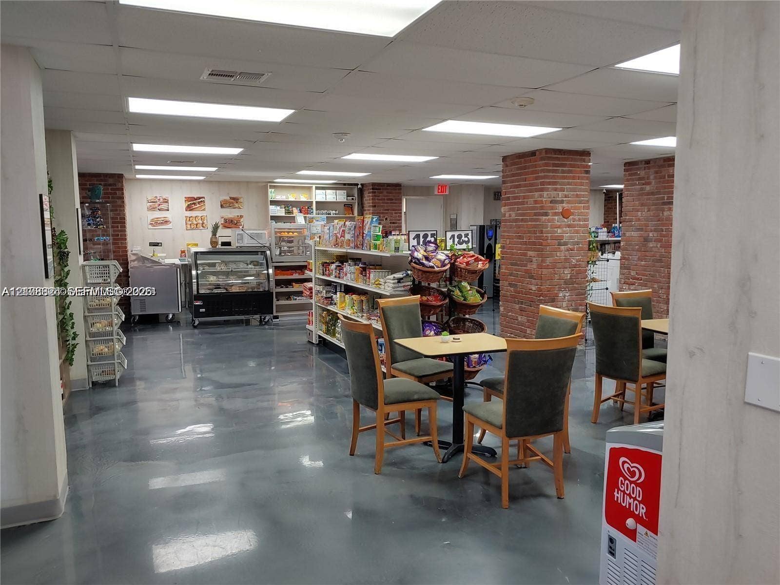 6039 Collins Avenue, #1208, Miami Beach, FL 33140 Expansive open-concept commercial space featuring high-gloss epoxy flooring, exposed brick support columns, integrated recessed ceiling lighting, and built-in service counters