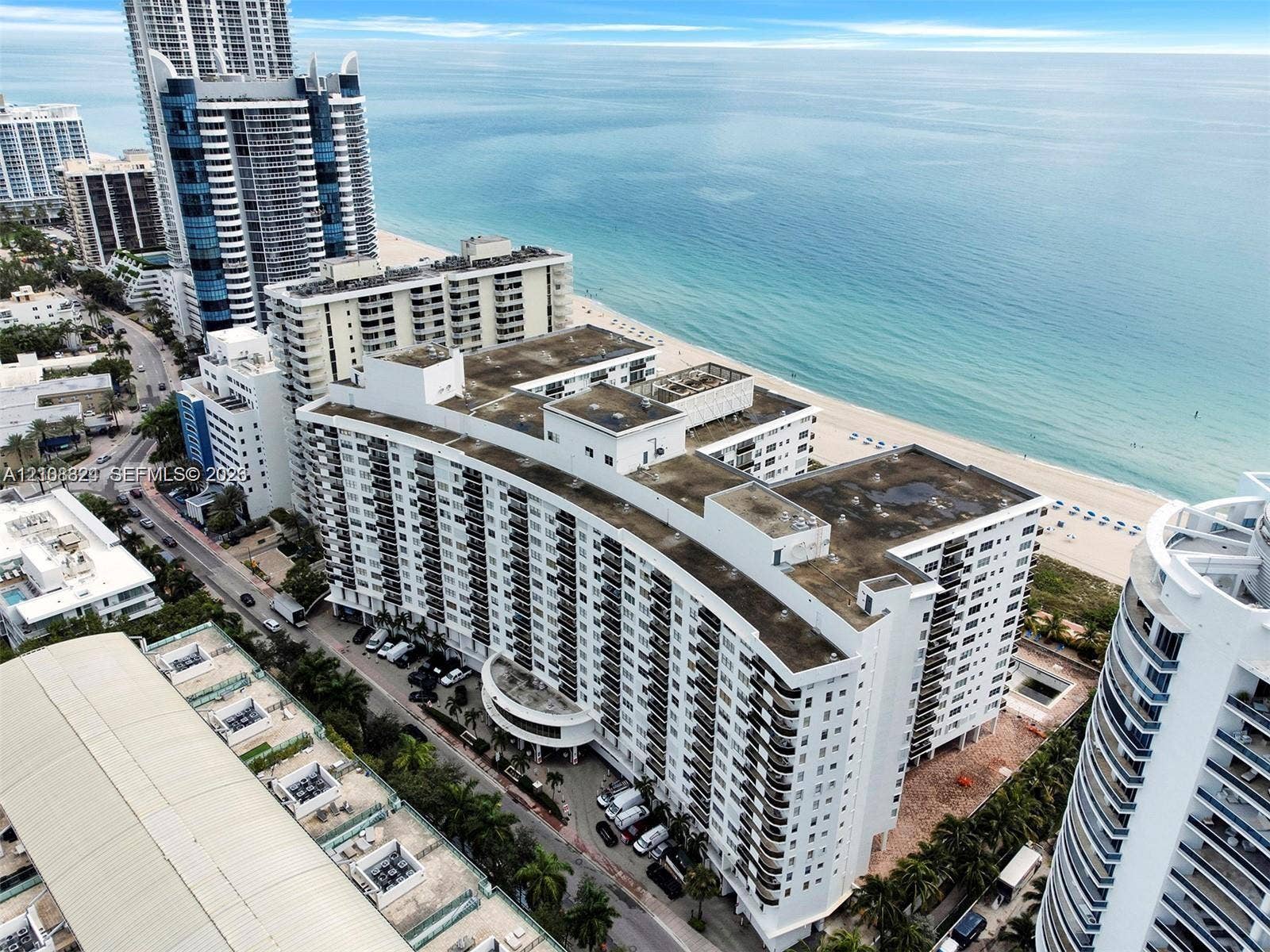 6039 Collins Avenue, #1208, Miami Beach, FL 33140 Mid-rise coastal residential building featuring a curved architectural design, private exterior balconies, and direct proximity to the oceanfront