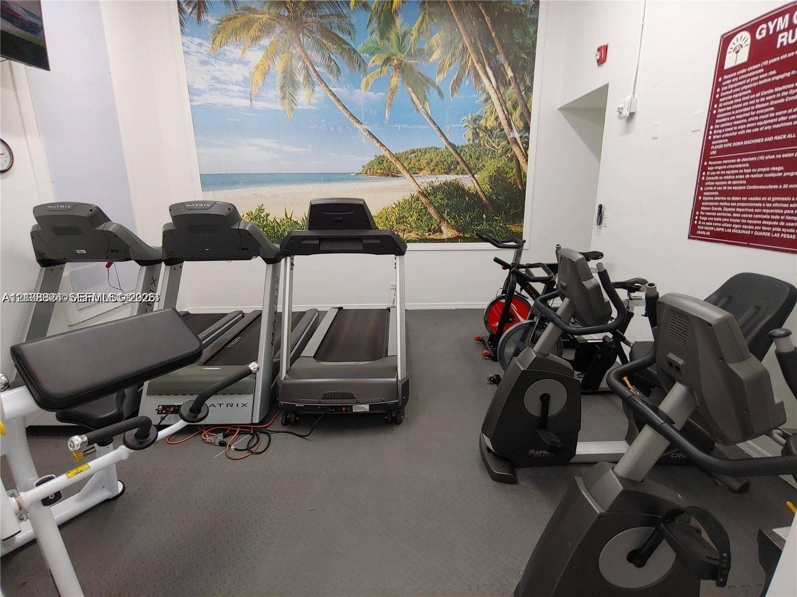 6039 Collins Avenue, #1208, Miami Beach, FL 33140 Fitness center featuring durable rubber flooring, wall-mounted tropical landscape mural, and recessed lighting