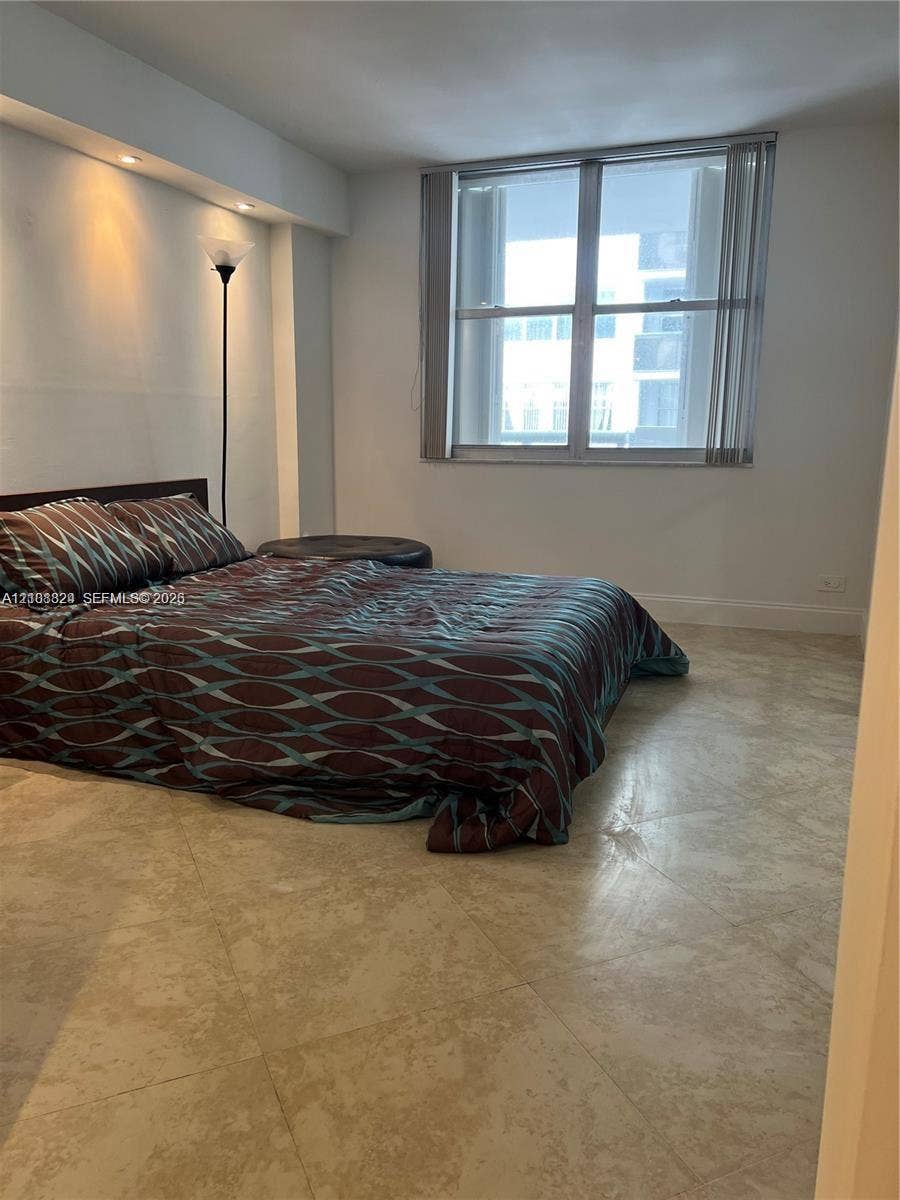 6039 Collins Avenue, #1208, Miami Beach, FL 33140 Neutral-toned tile flooring, recessed ceiling lighting, and a large multi-pane window with vertical blinds