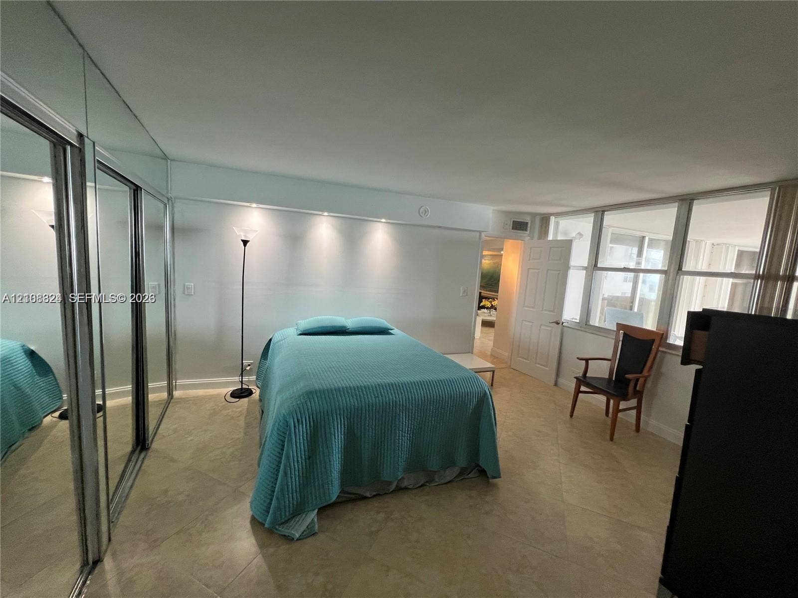 6039 Collins Avenue, #1208, Miami Beach, FL 33140 Spacious room featuring floor-to-ceiling mirror-paneled closet doors, neutral tile flooring, built-in recessed ceiling lighting, and a wall of large windows