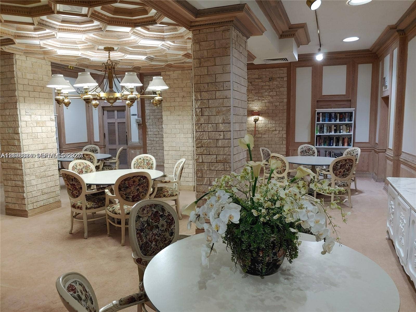 6039 Collins Avenue, #1208, Miami Beach, FL 33140 Intricate coffered ceiling, exposed stone columns, custom wood wall paneling, built-in shelving, and tiered brass chandelier