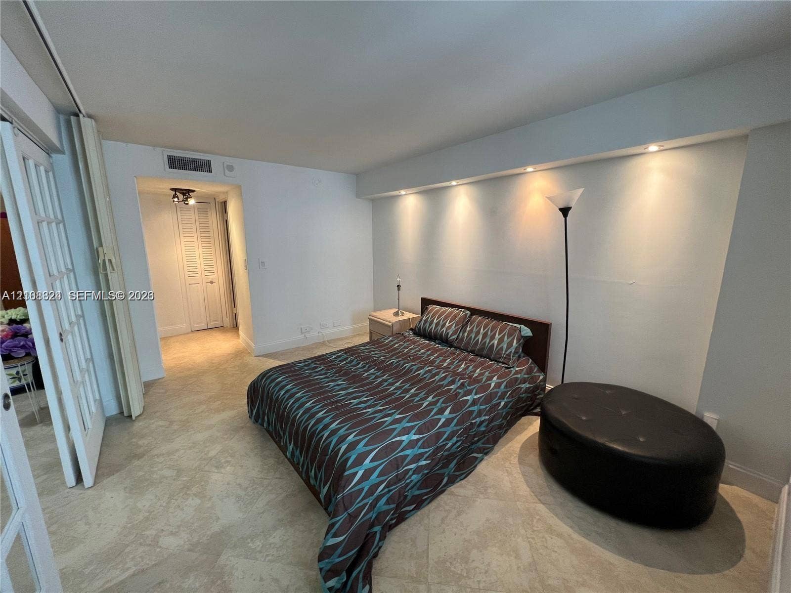 6039 Collins Avenue, #1208, Miami Beach, FL 33140 Interior space featuring neutral stone-finish tile flooring, recessed cove lighting, and French-style glass pane double doors
