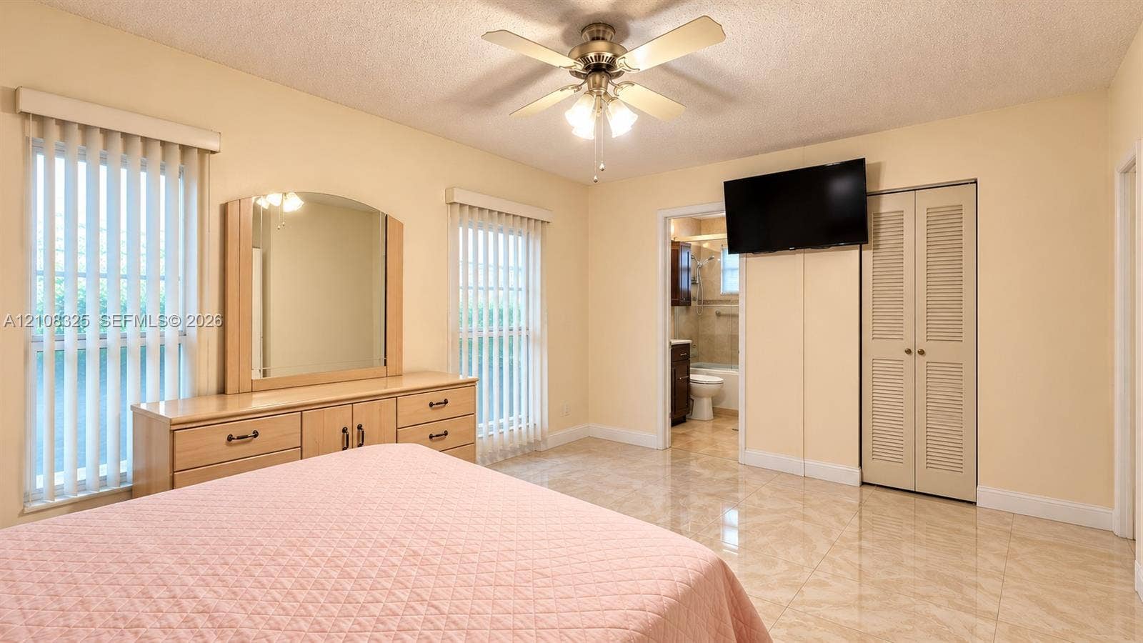 7931 W 6th Avenue, Hialeah, FL 33014 Room featuring ceramic tile flooring, dual windows with vertical blinds, a ceiling fan with integrated lighting, and a closet with louvered doors