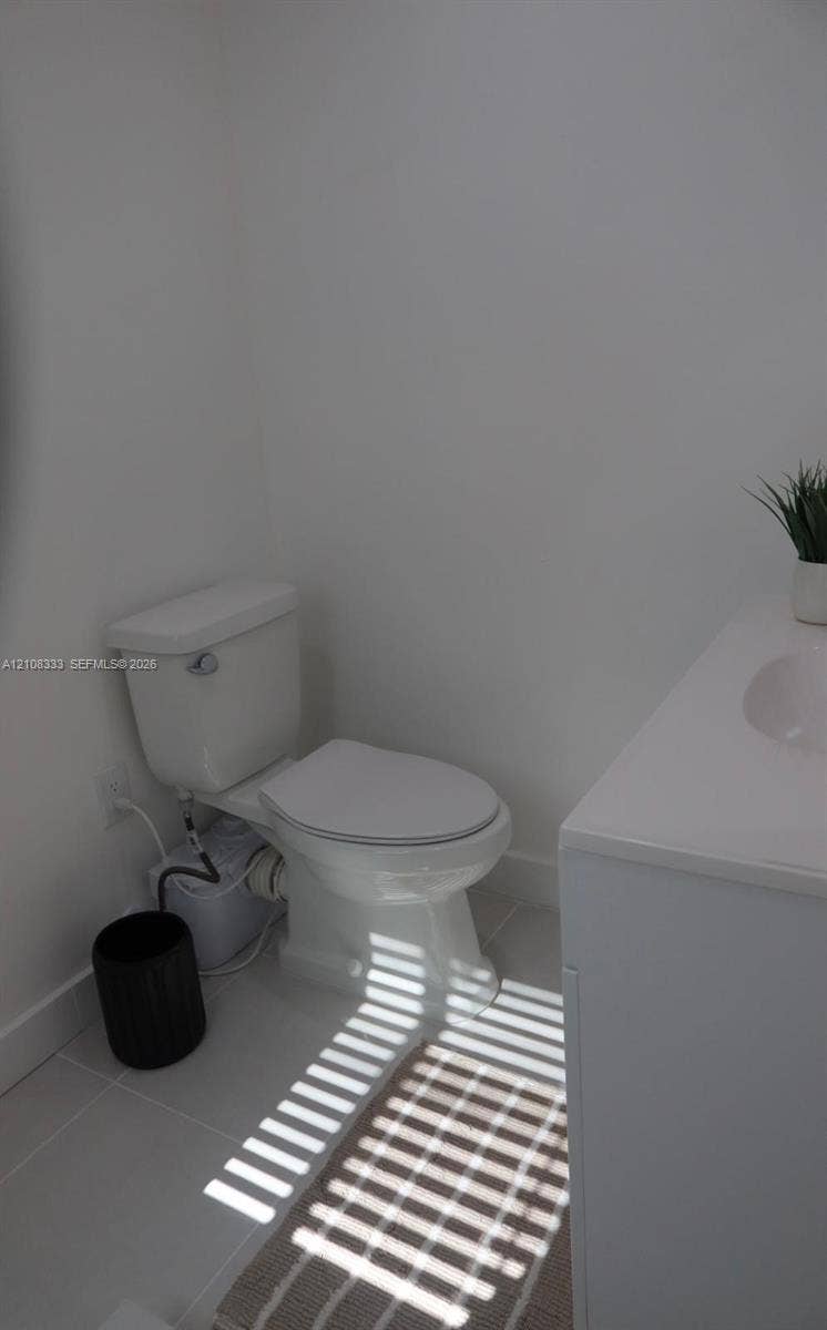 10450 SW 166th Terrace, #0, Miami, Miami, FL 33157 White ceramic toilet and modern vanity with a white countertop and integrated sink, set against neutral tile flooring
