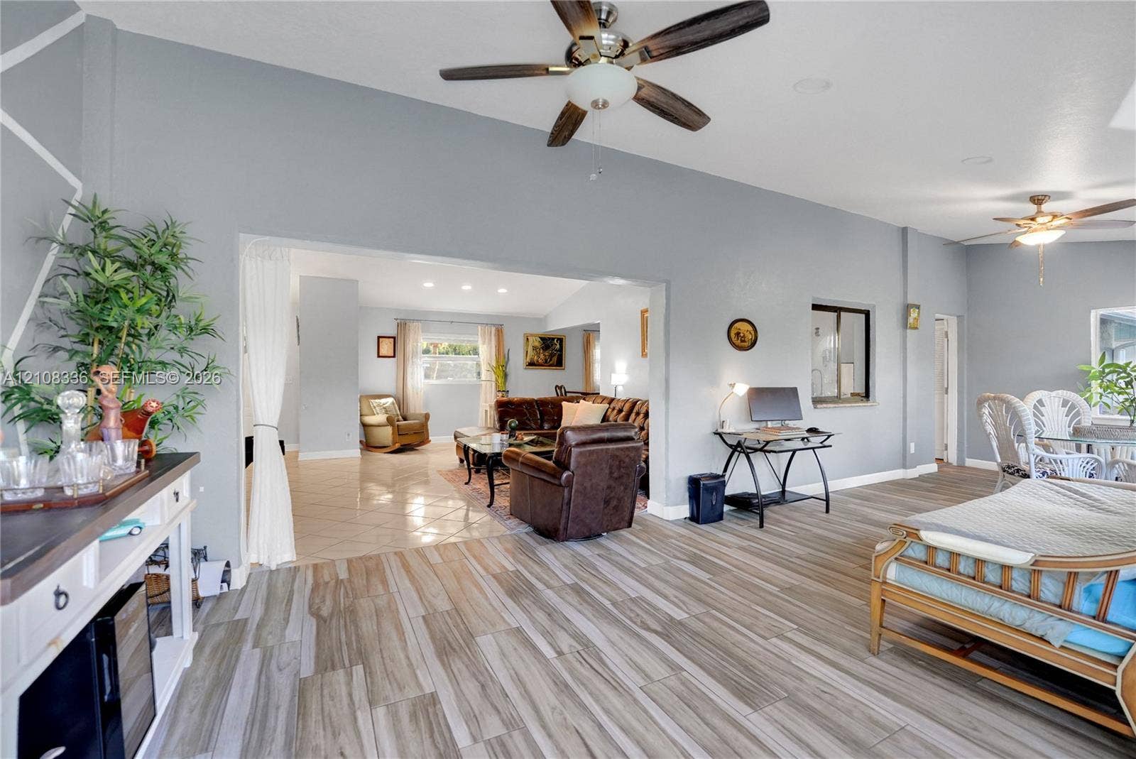 6311 Hitchin Post Way, Delray Beach, FL 33484 Open-concept interior featuring wood-finish flooring, vaulted ceilings, dual ceiling fans, and neutral wall tones