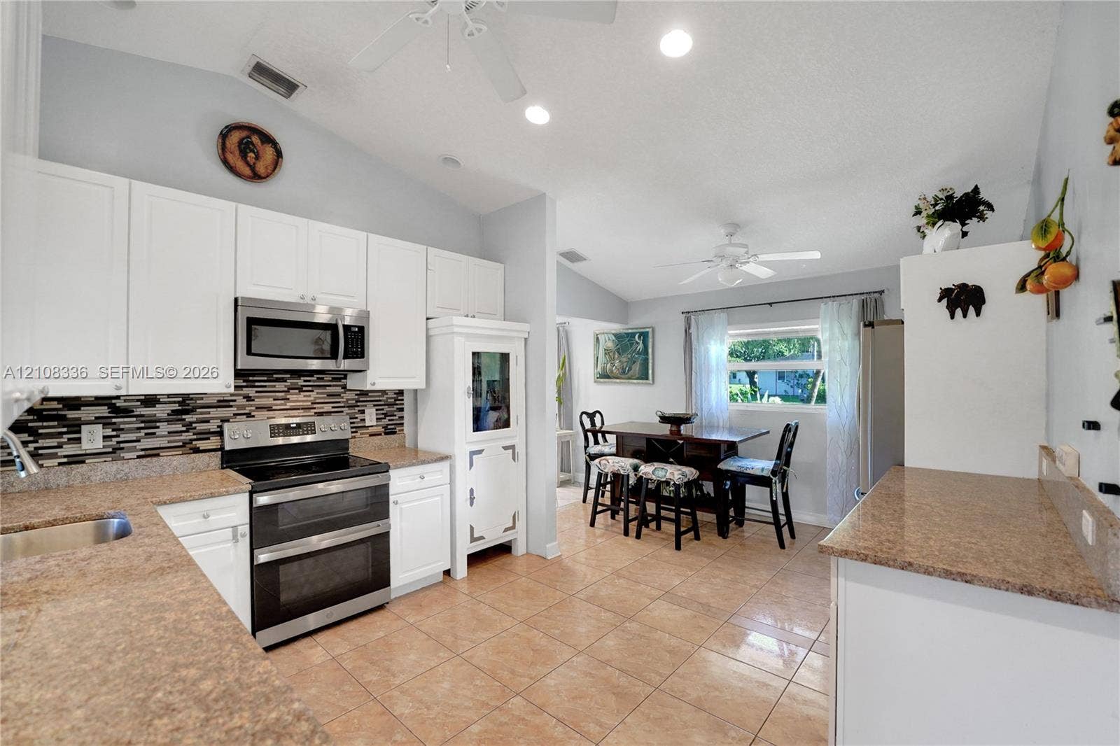 6311 Hitchin Post Way, Delray Beach, FL 33484 Kitchen featuring white cabinetry, stone-finish countertops, stainless steel appliances, multi-toned mosaic tile backsplash, and ceramic tile flooring