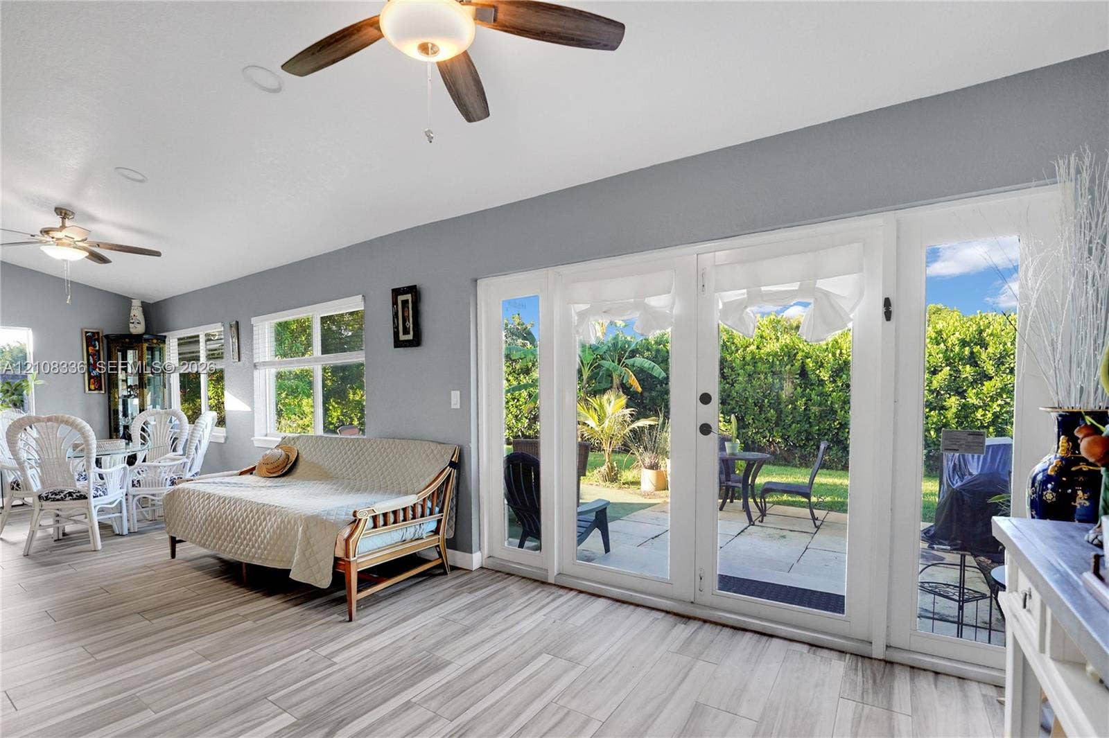 6311 Hitchin Post Way, Delray Beach, FL 33484 Living area featuring wood-finish tile flooring, recessed lighting, dual ceiling fans, and multi-panel glass doors opening to a stone-paved patio