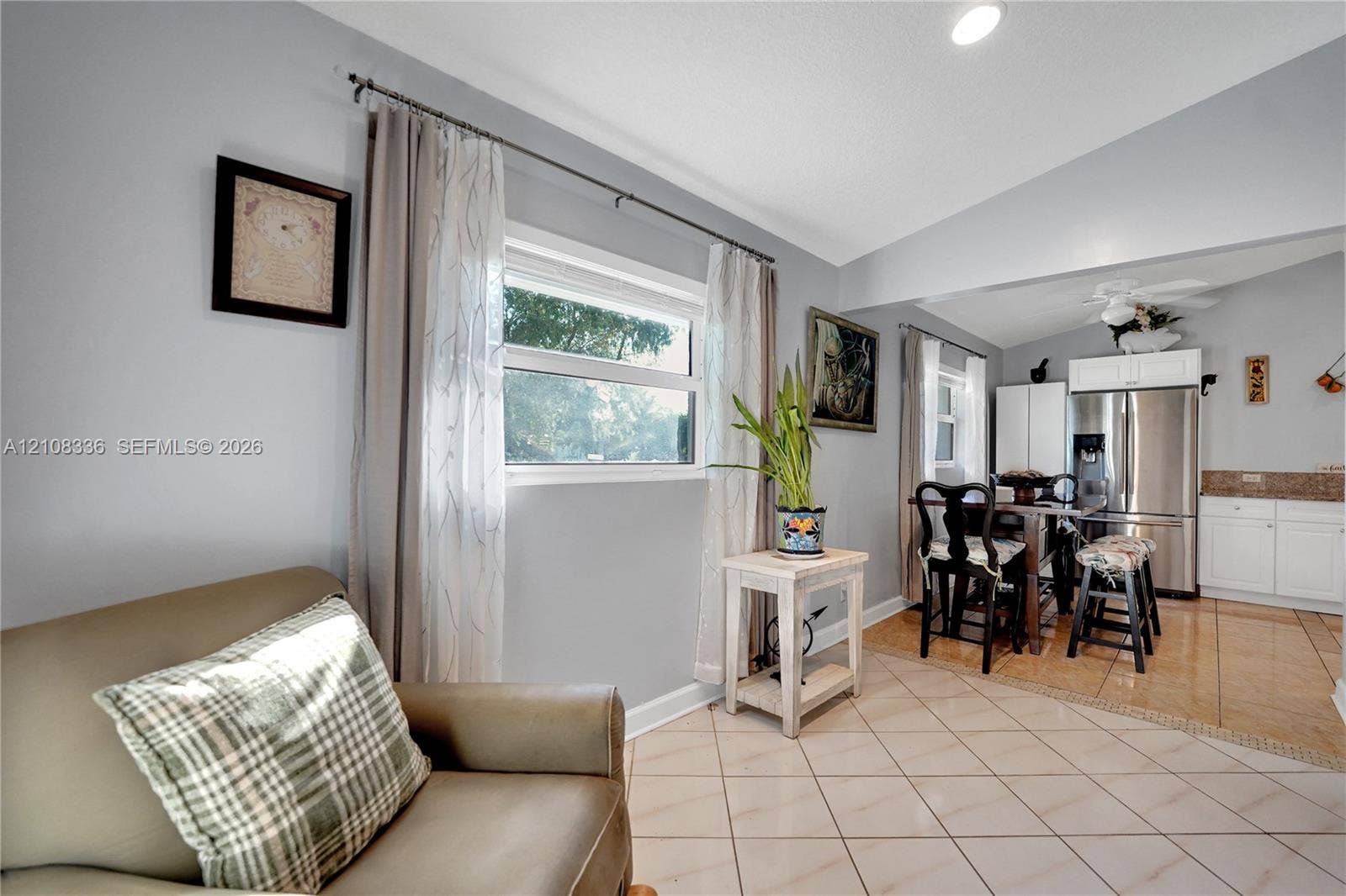 6311 Hitchin Post Way, Delray Beach, FL 33484 Open-concept interior featuring light-toned diagonal tile flooring, vaulted ceilings, recessed lighting, and white kitchen cabinetry with stainless steel appliances