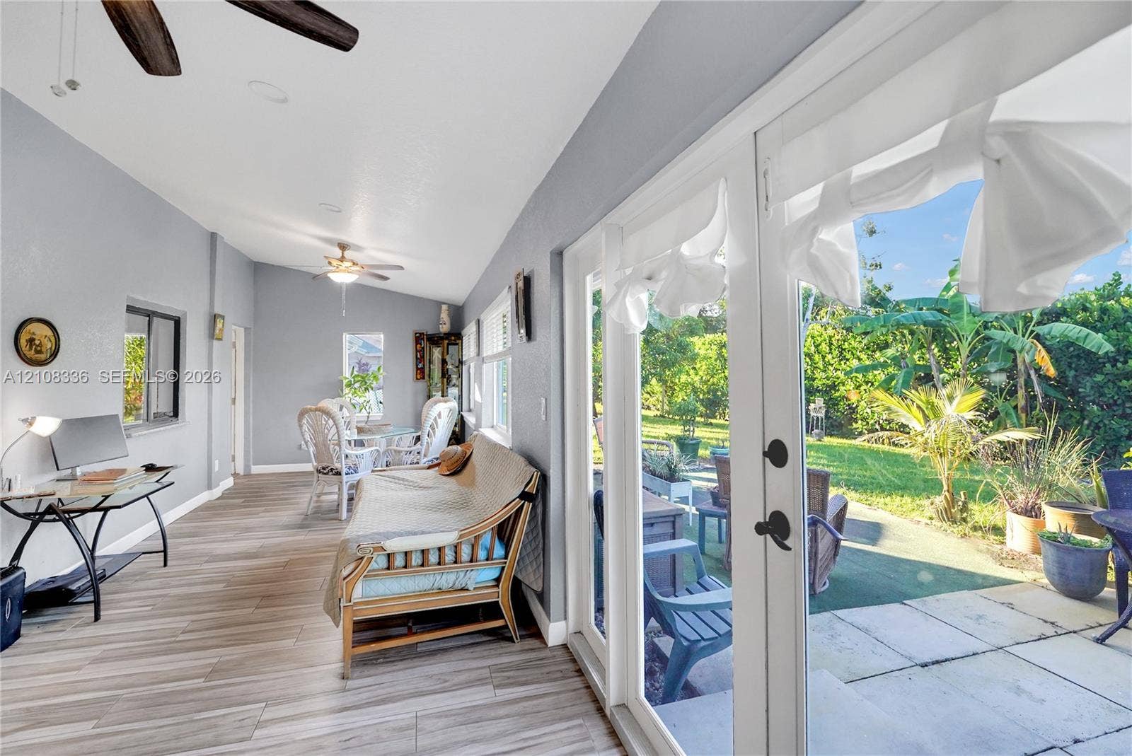 6311 Hitchin Post Way, Delray Beach, FL 33484 Sunroom featuring wood-finish flooring, recessed lighting, dual ceiling fans, and full-length glass panel doors opening to a paved patio