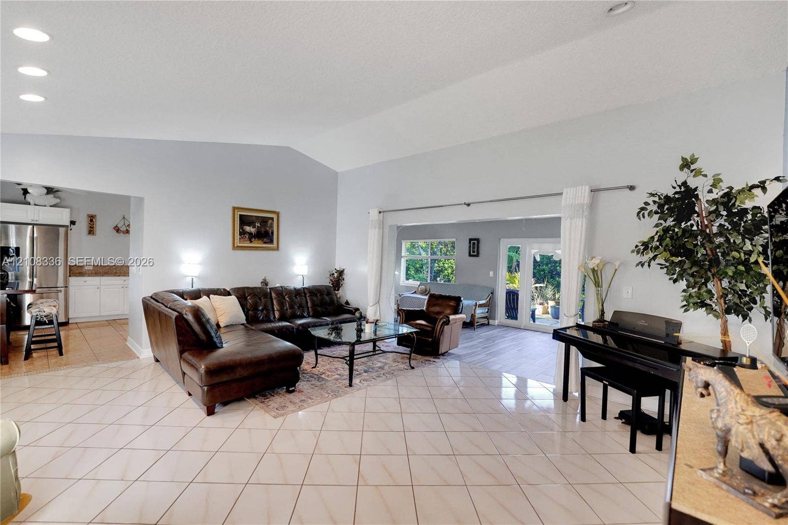 6311 Hitchin Post Way, Delray Beach, FL 33484 Open-concept interior featuring vaulted ceilings, neutral wall tones, large-format tile flooring, and recessed lighting