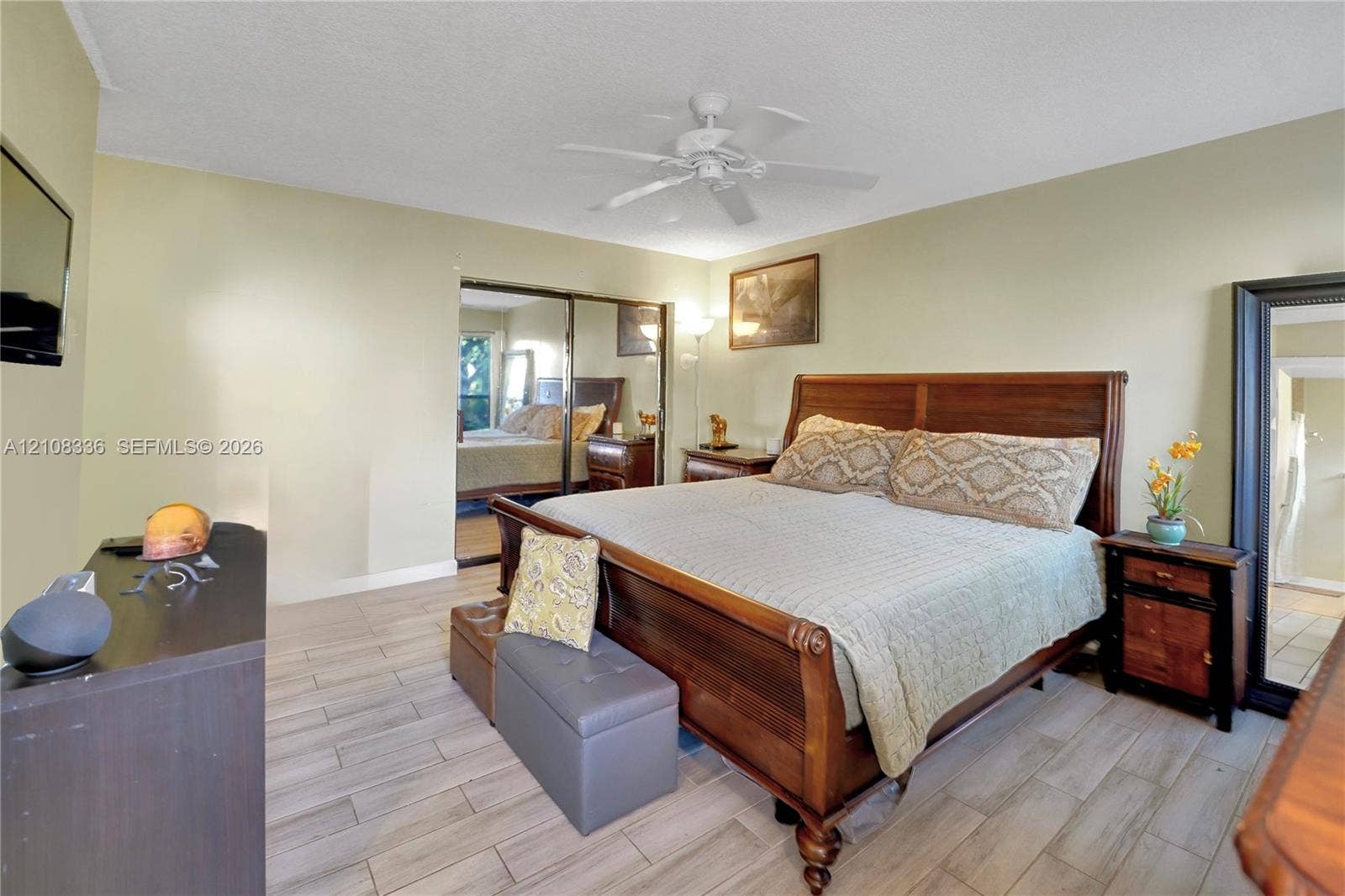 6311 Hitchin Post Way, Delray Beach, FL 33484 Neutral-toned walls featuring wood-finish tile flooring, ceiling fan with integrated lighting, and mirrored closet doors