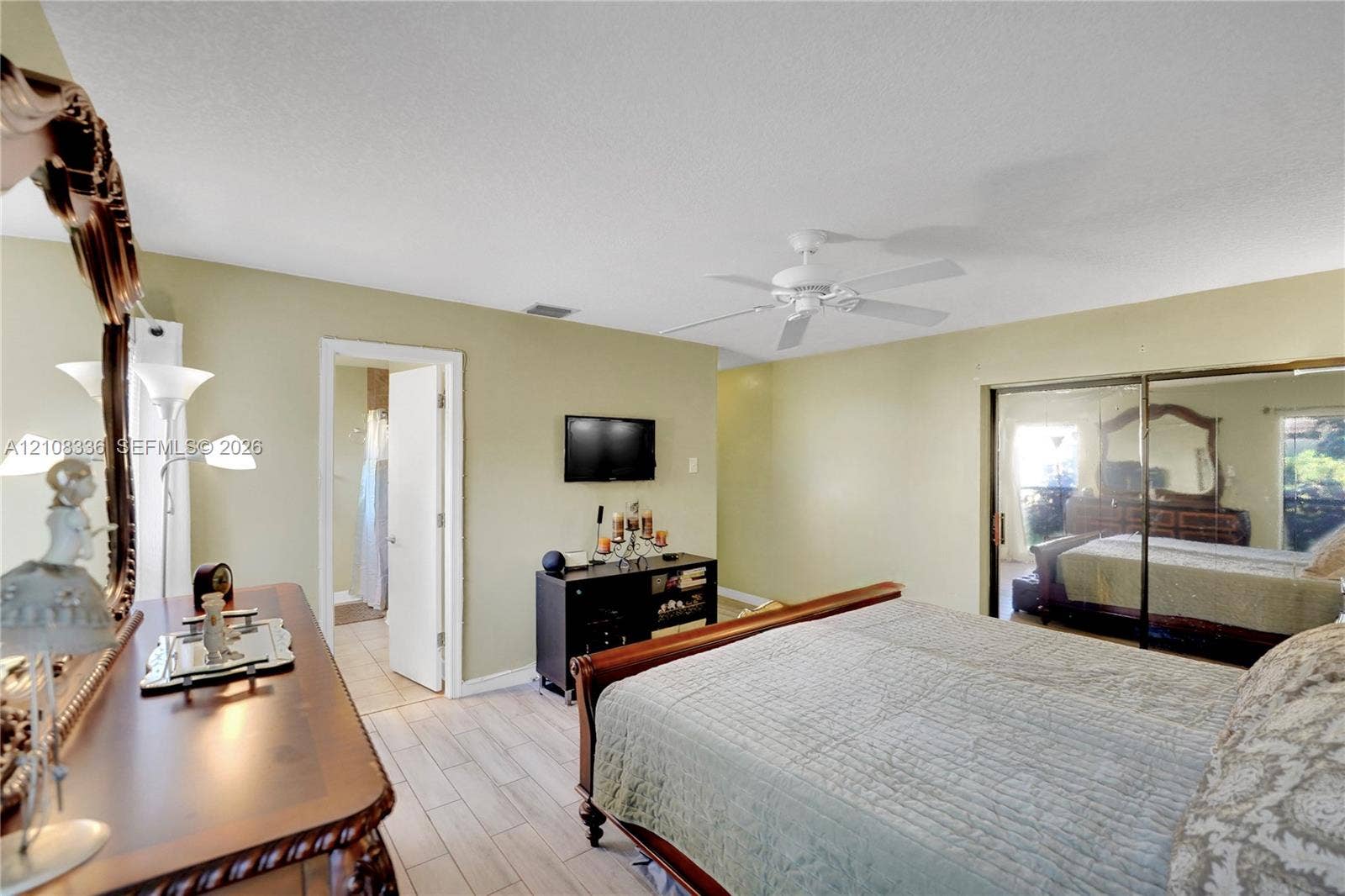6311 Hitchin Post Way, Delray Beach, FL 33484 Neutral-toned bedroom featuring wood-finish tile flooring, ceiling fan, and sliding mirrored closet doors