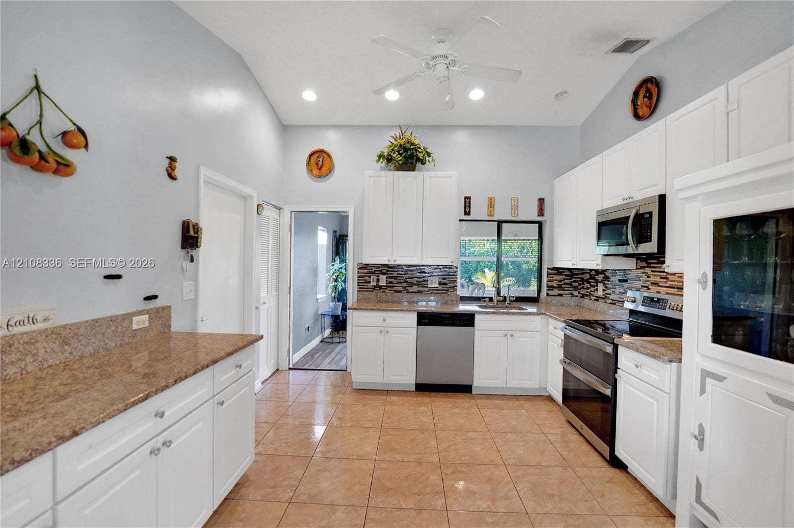 6311 Hitchin Post Way, Delray Beach, FL 33484 Kitchen featuring white cabinetry, stone-surface countertops, tile flooring, stainless steel appliances, and multi-tone decorative tile backsplash