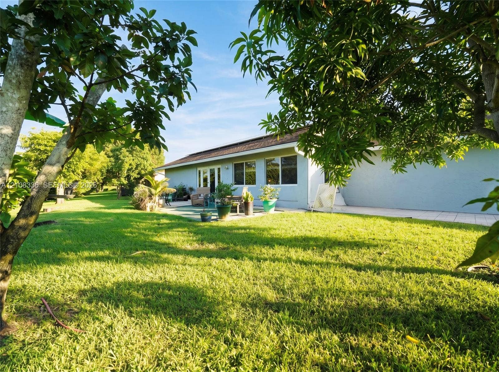 6311 Hitchin Post Way, Delray Beach, FL 33484 Expansive backyard featuring a sprawling lawn, mature trees, and a paved patio area