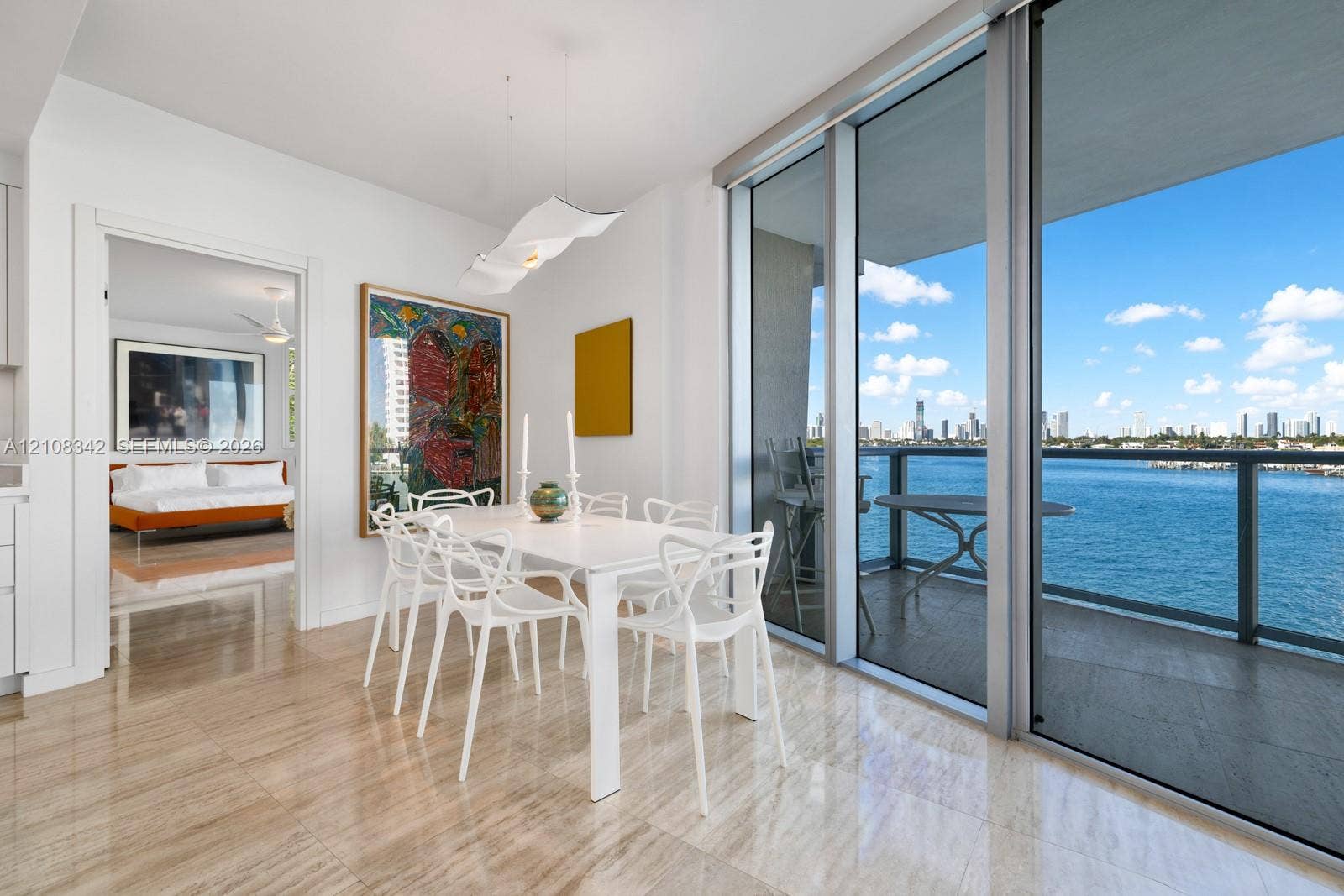 Floor-to-ceiling sliding glass doors, private balcony with metal railing, polished stone flooring, and sculptural pendant lighting
