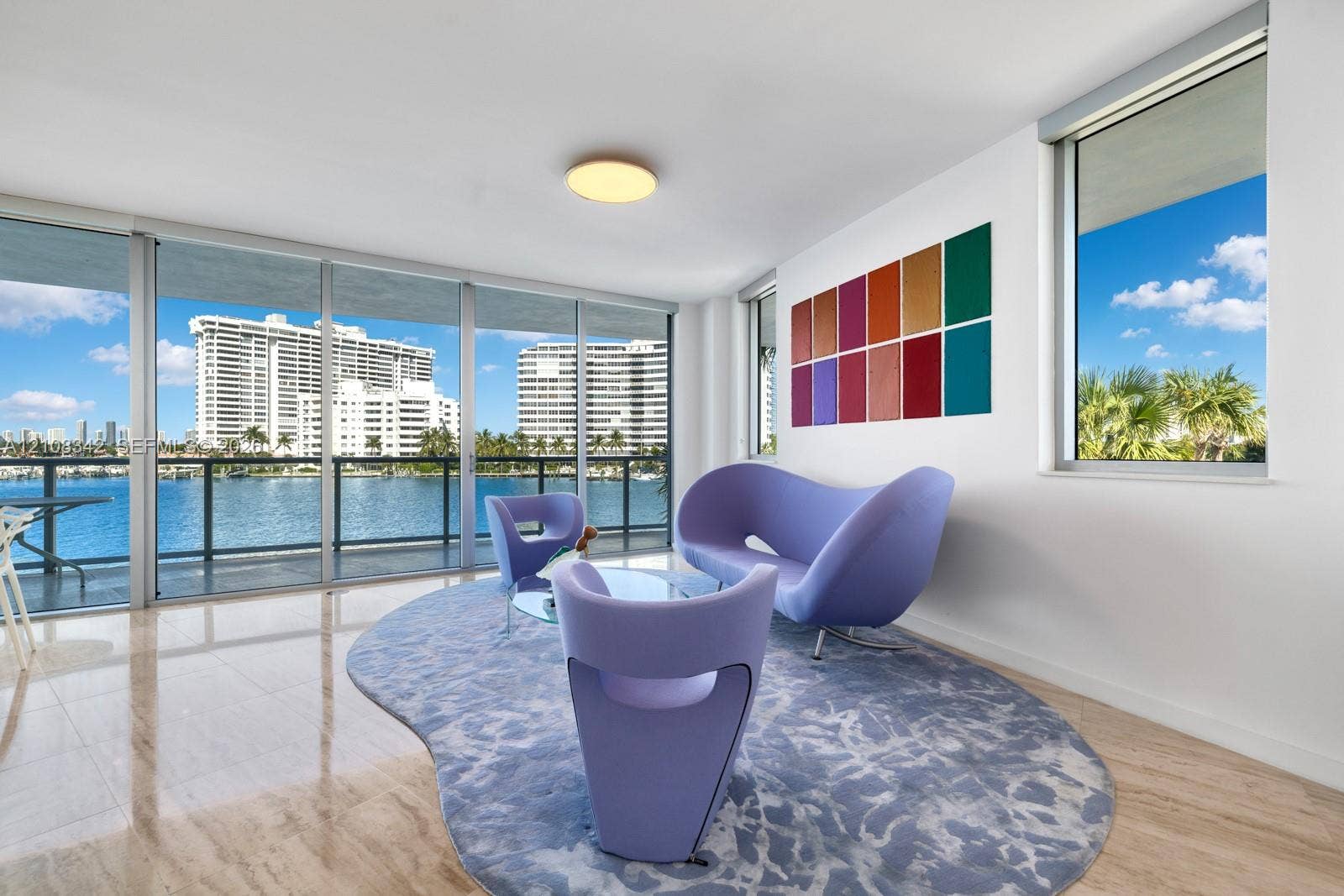 Floor-to-ceiling windows, polished stone flooring, recessed ceiling lighting, and a metal-framed balcony railing